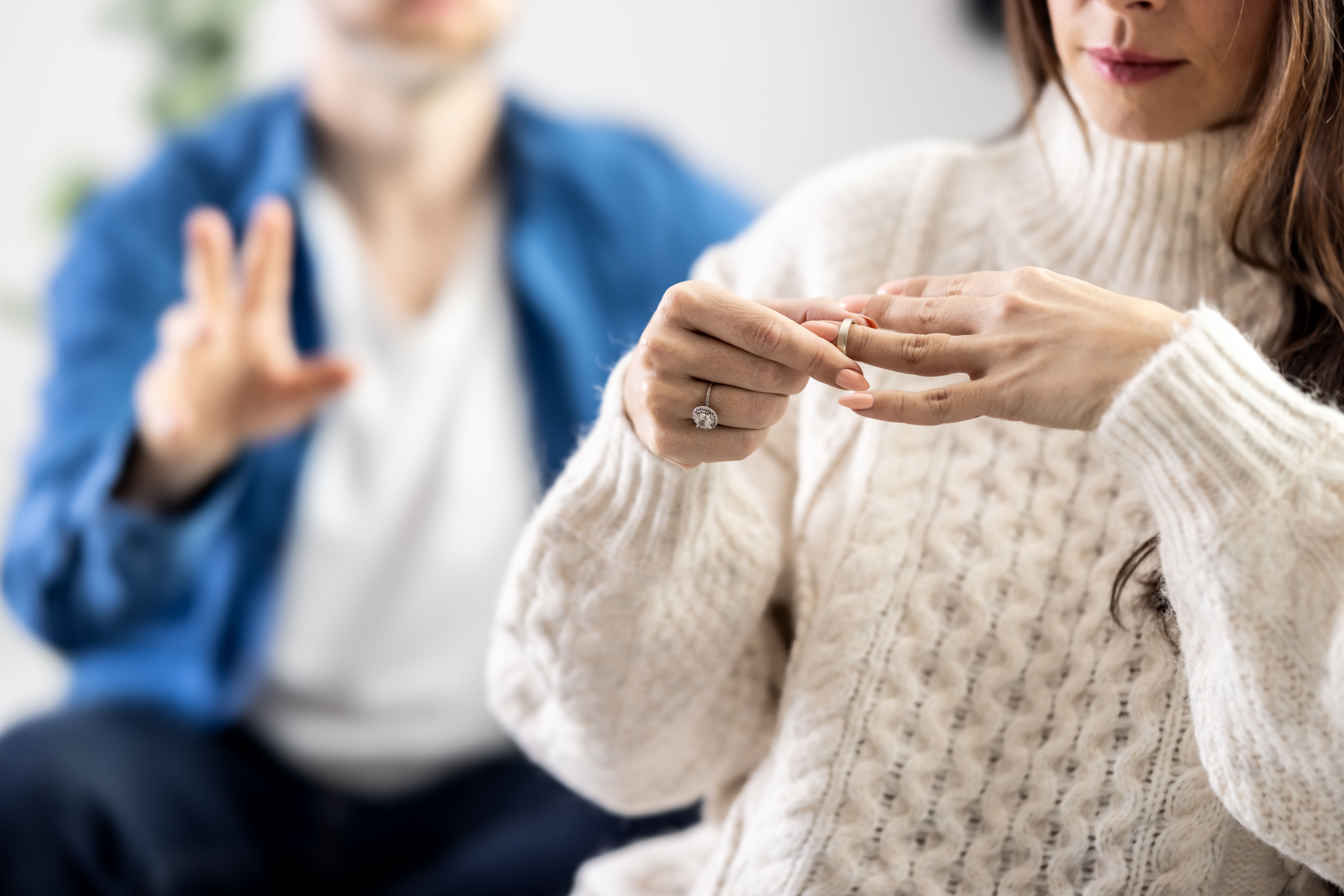 Frau nimmt traurigen Blick ab, während sie ihren Ehering vom Finger zieht.
