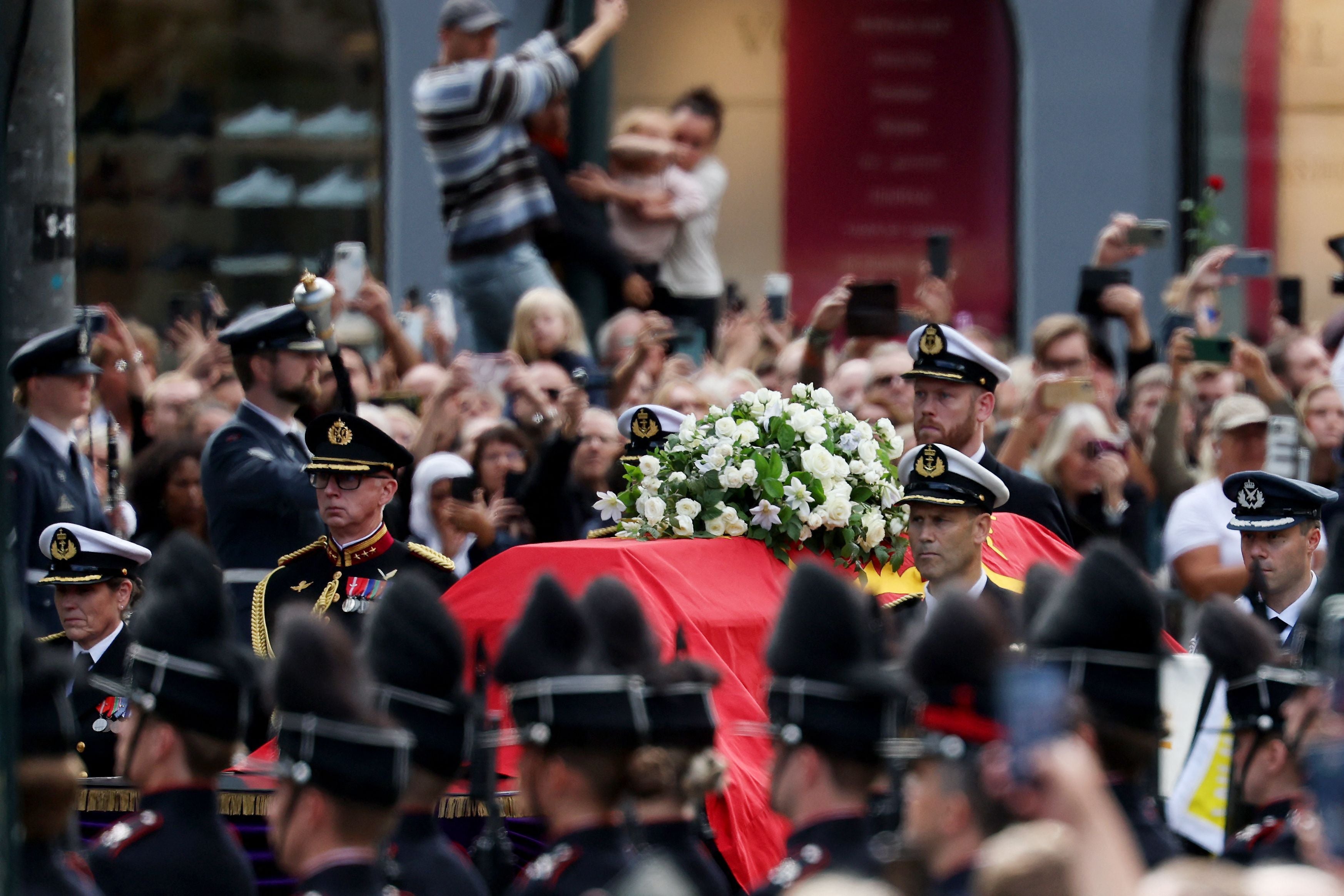 Menschenmenge verfolgt Sarg mit Blumen in königlicher Prozession durch Oslo.