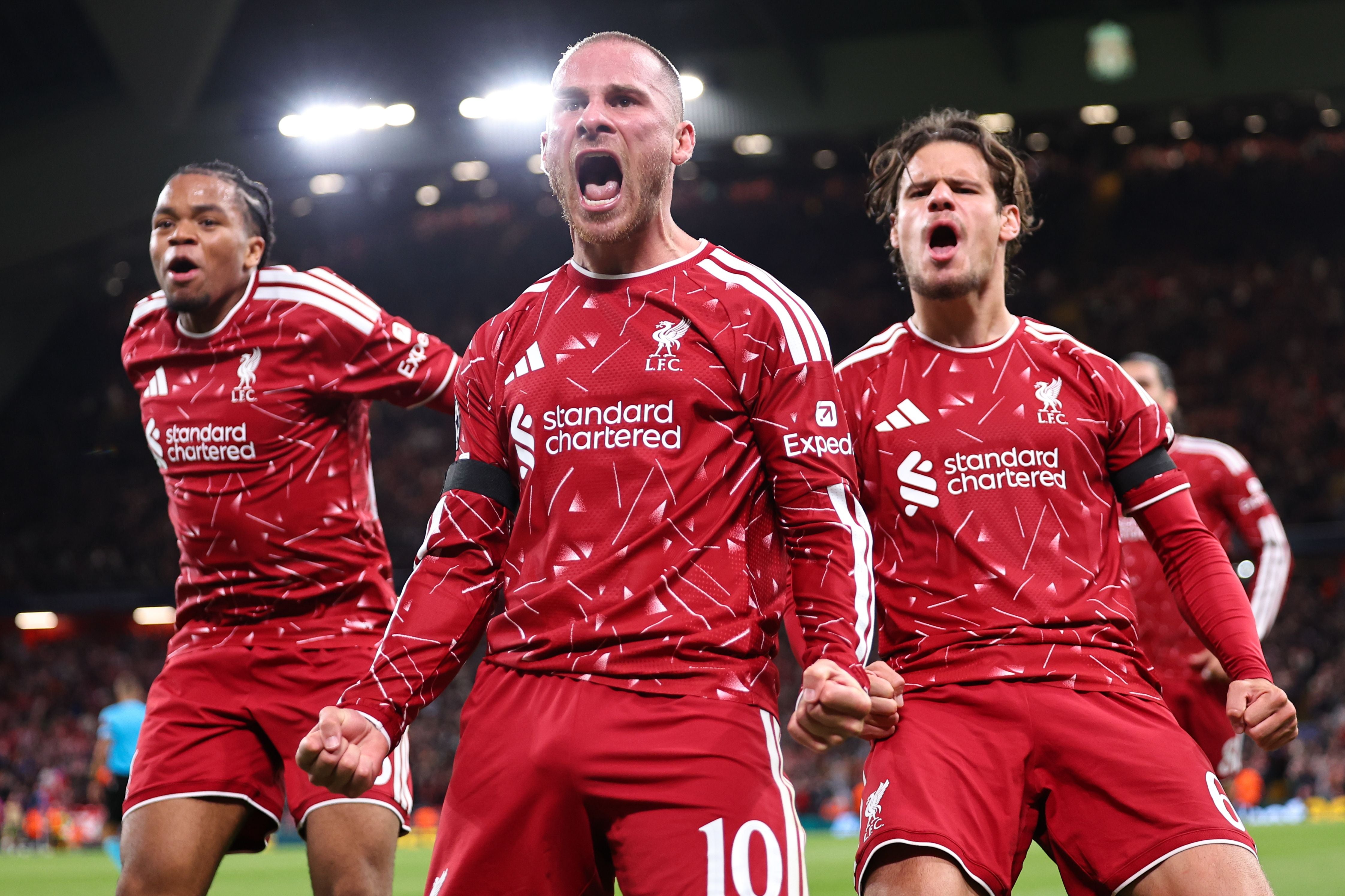 Drei Liverpool-Spieler jubeln lautstark im roten Trikot nach einem Torerfolg.