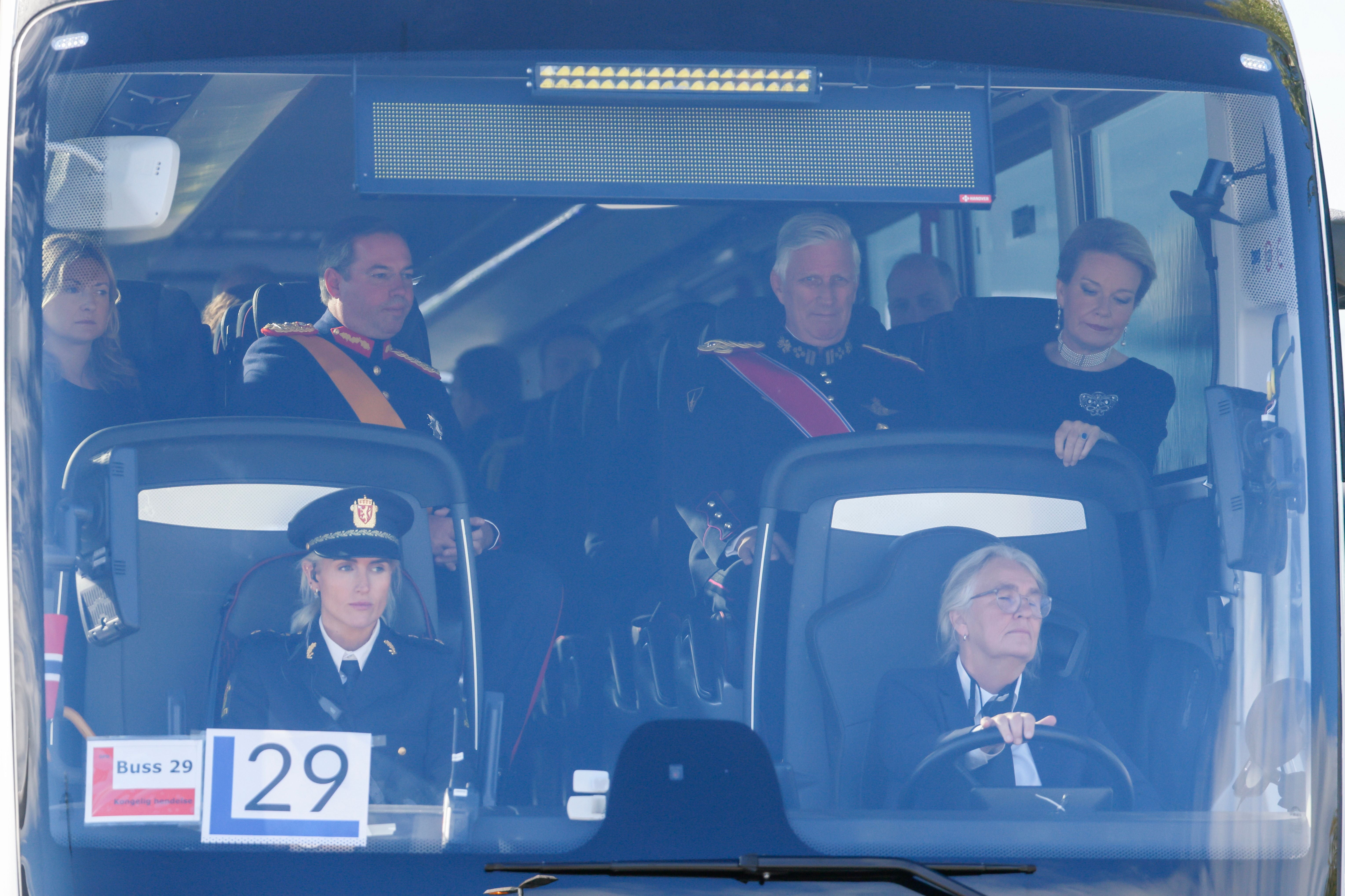 König Philippe und Königin Mathilde von Belgien sitzen in einem Bus mit anderen Passagieren.