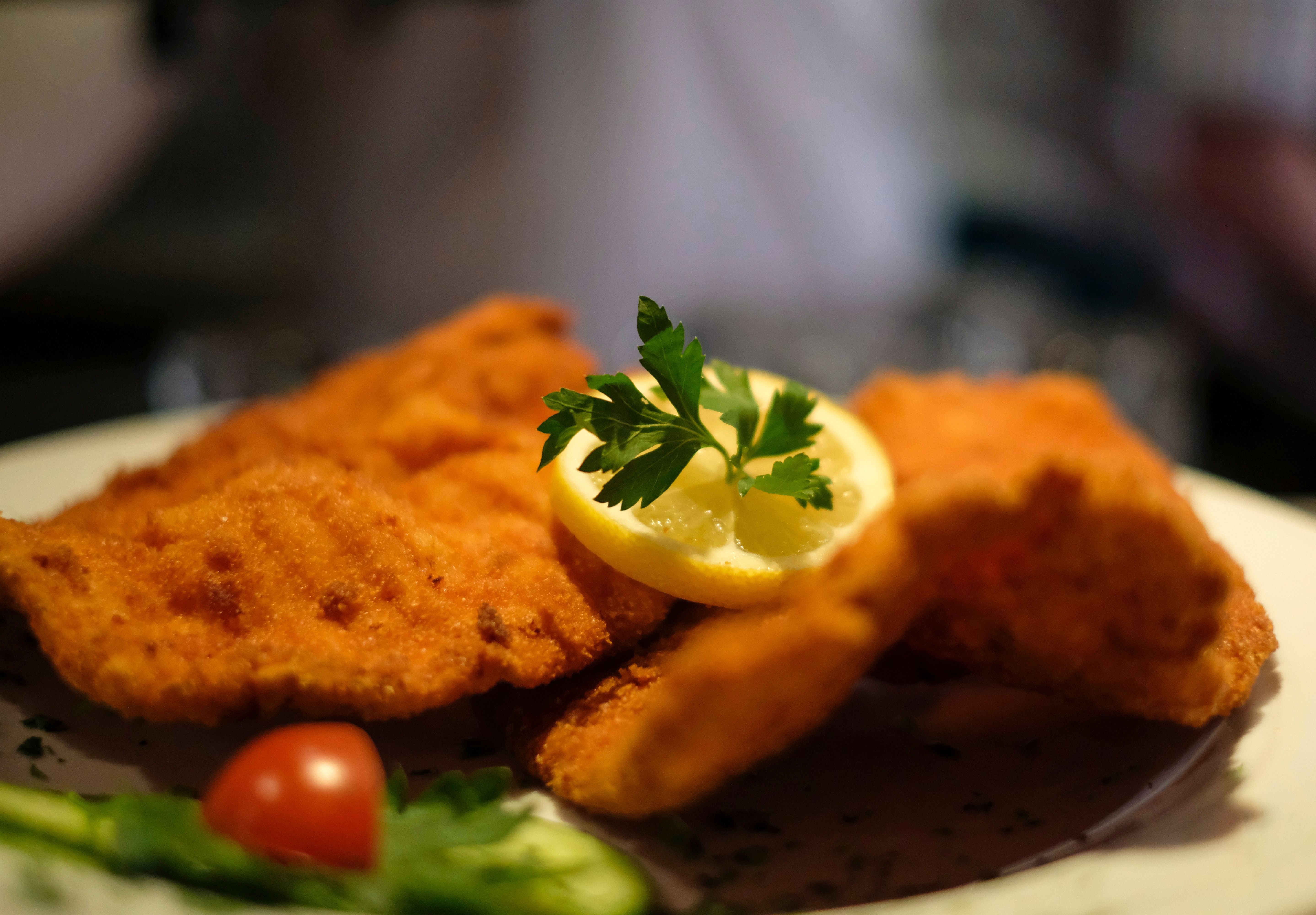 Nahaufnahme eines Wiener Schnitzels mit Zitronenscheibe und Petersilie garniert.