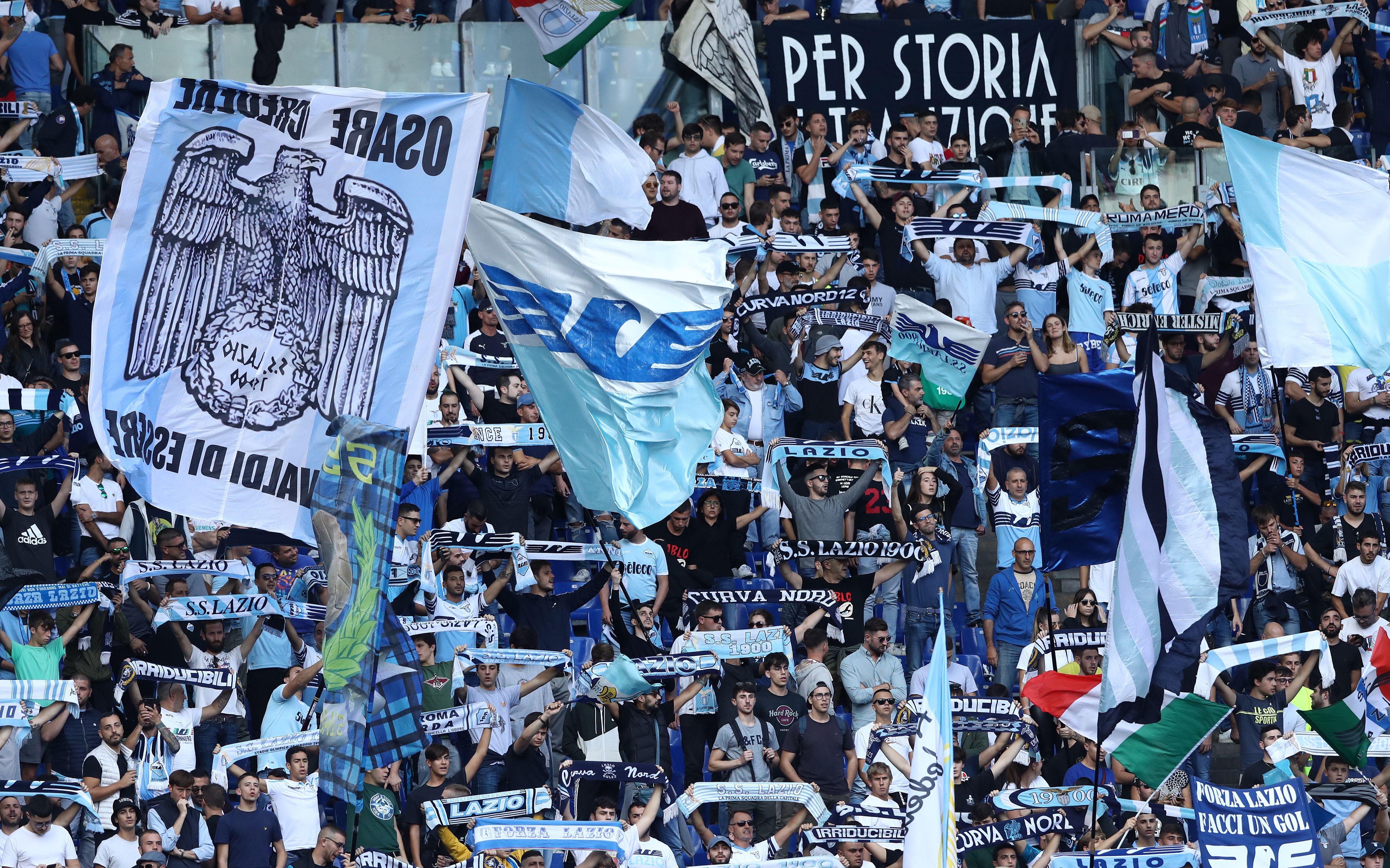 Lazio-Fans schwenken Fahnen und halten Schals im Stadion während eines Fußballspiels.