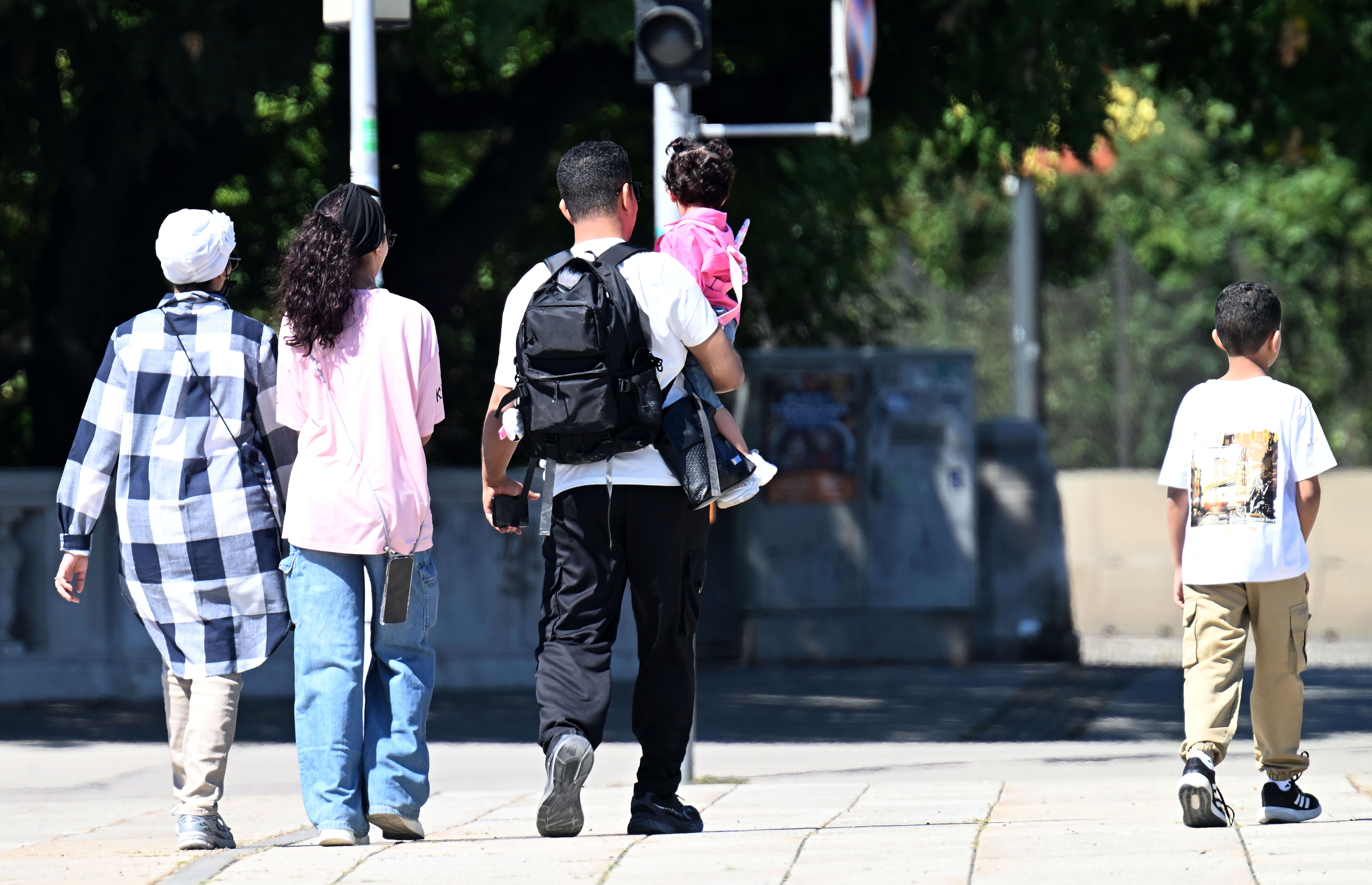 Eine Familie mit Kindern geht an einem sonnigen Tag gemeinsam eine Straße entlang.