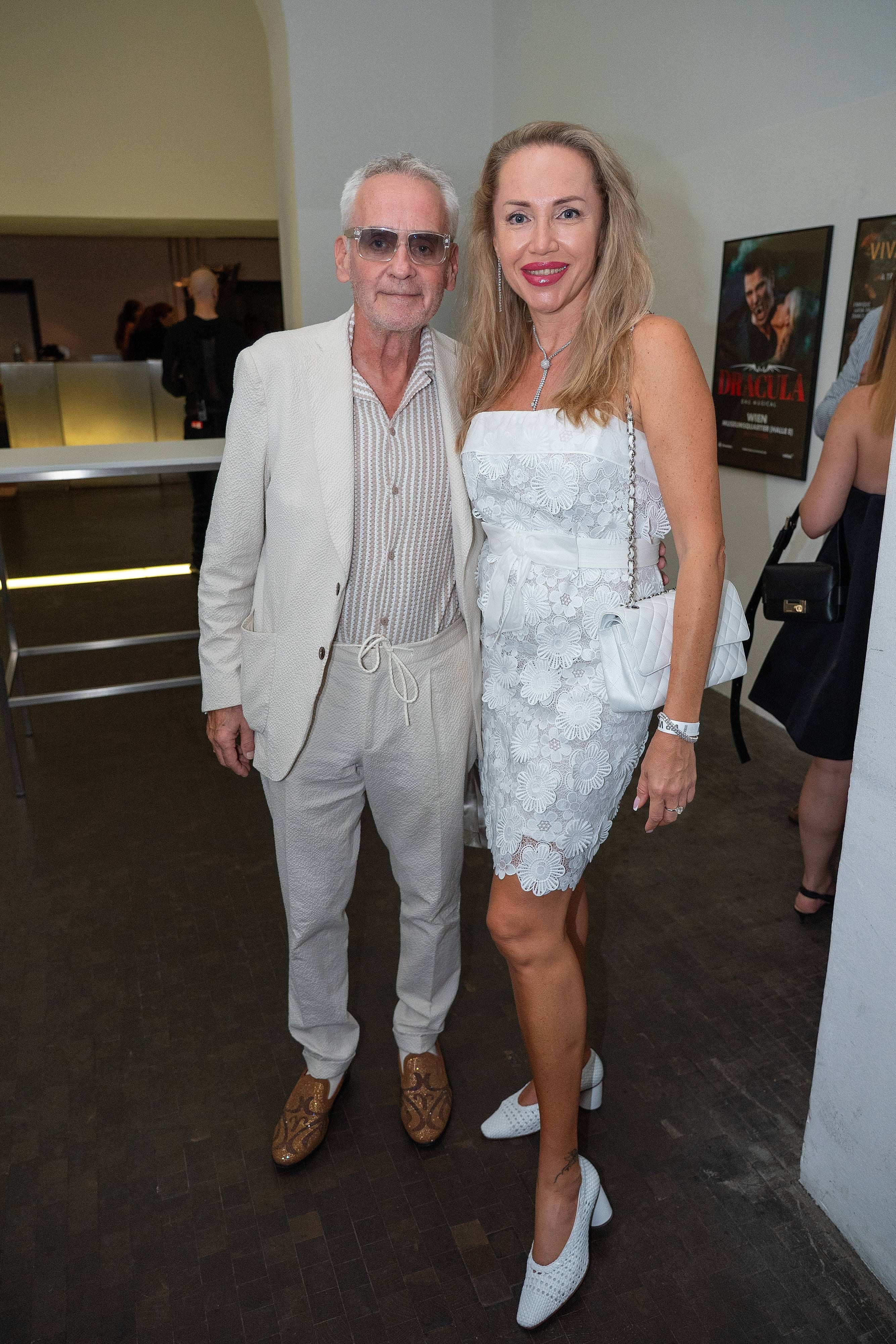 Ein Mann und eine Frau posieren schick gekleidet bei der Vienna Fashion Week Eröffnung.