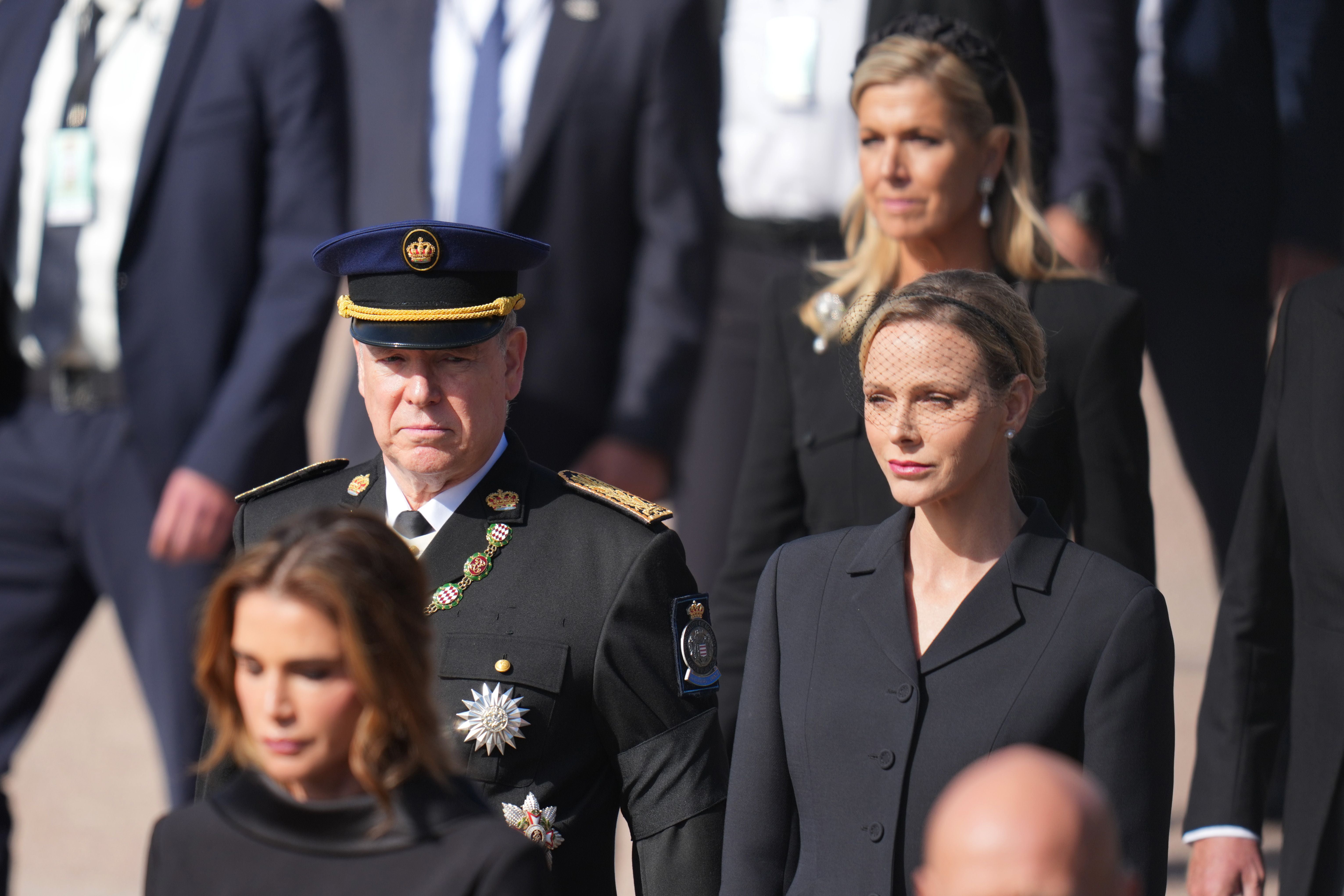 Prinz Albert II. und Prinzessin Charlène von Monaco in Trauerkleidung bei einer Beerdigung.
