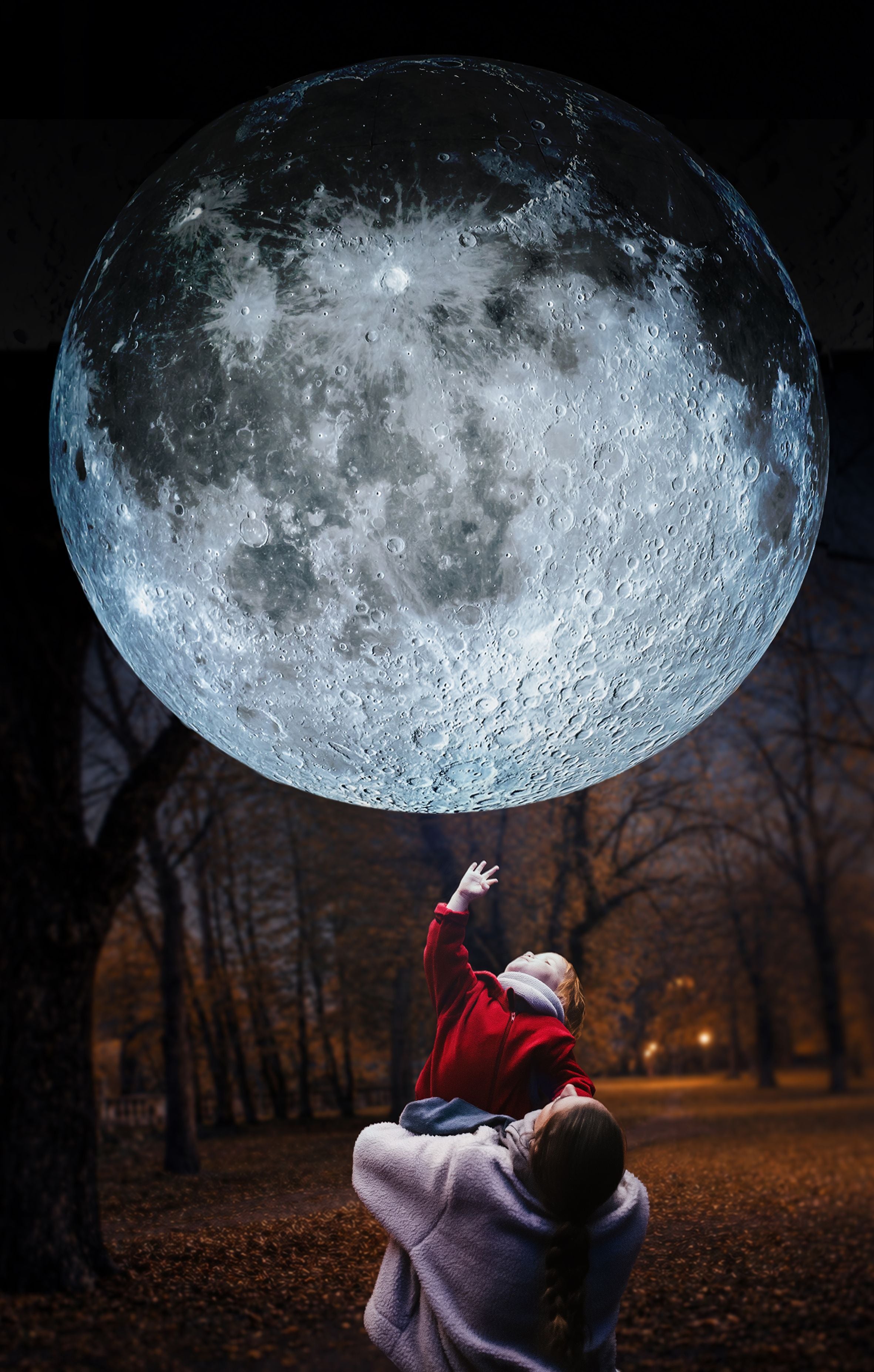 Frau hebt Kind hoch, das nach einem riesigen Mond über ihnen im Park greift.