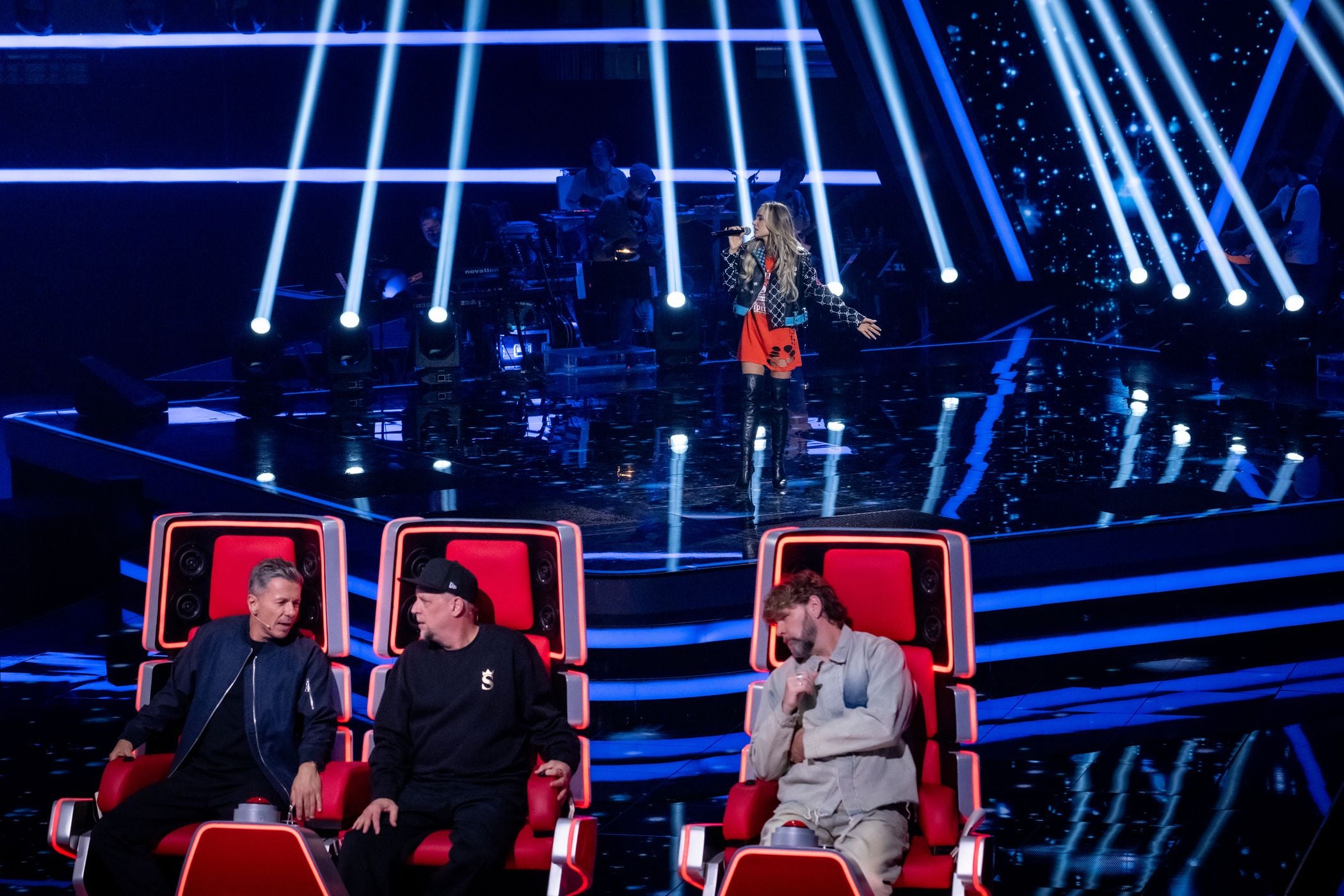 Eine Sängerin tritt auf einer Bühne bei "The Voice of Germany" vor drei Juroren auf.