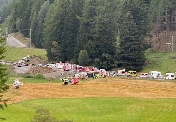 Mehrere Rettungsfahrzeuge und Hubschrauber bei einem Einsatz nahe einem Waldrand in der Schweiz.
