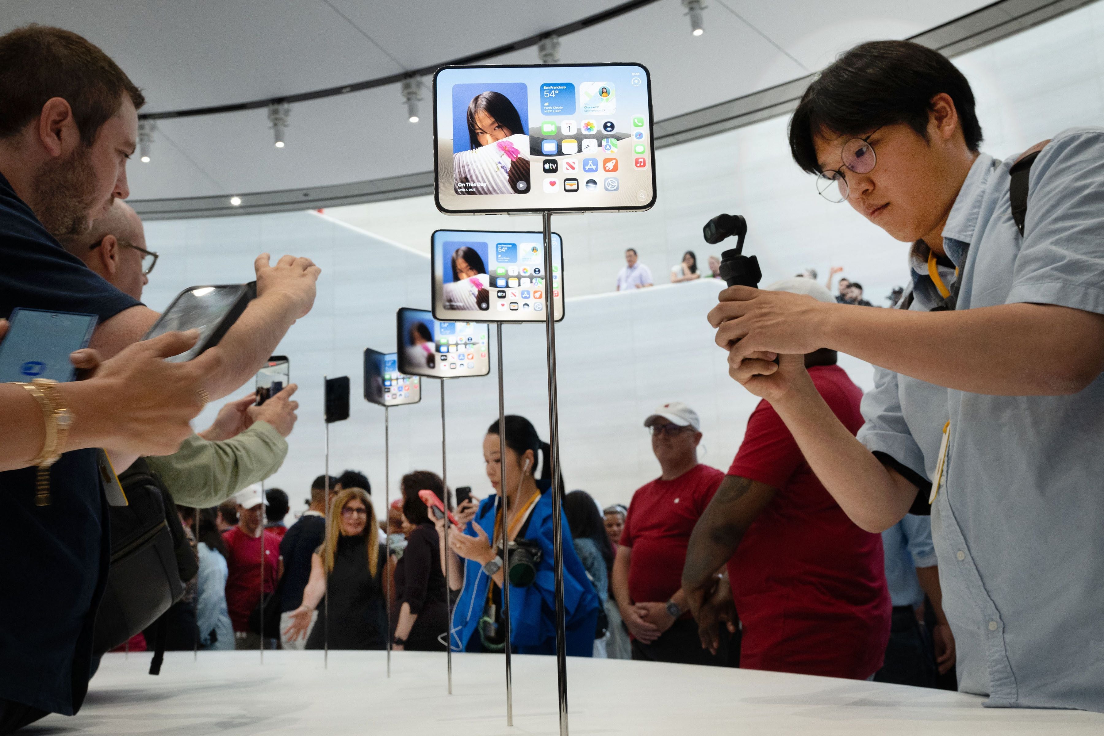 Menschen fotografieren neue iPhone Duo Modelle auf einer Ausstellung im Steve Jobs Theater.