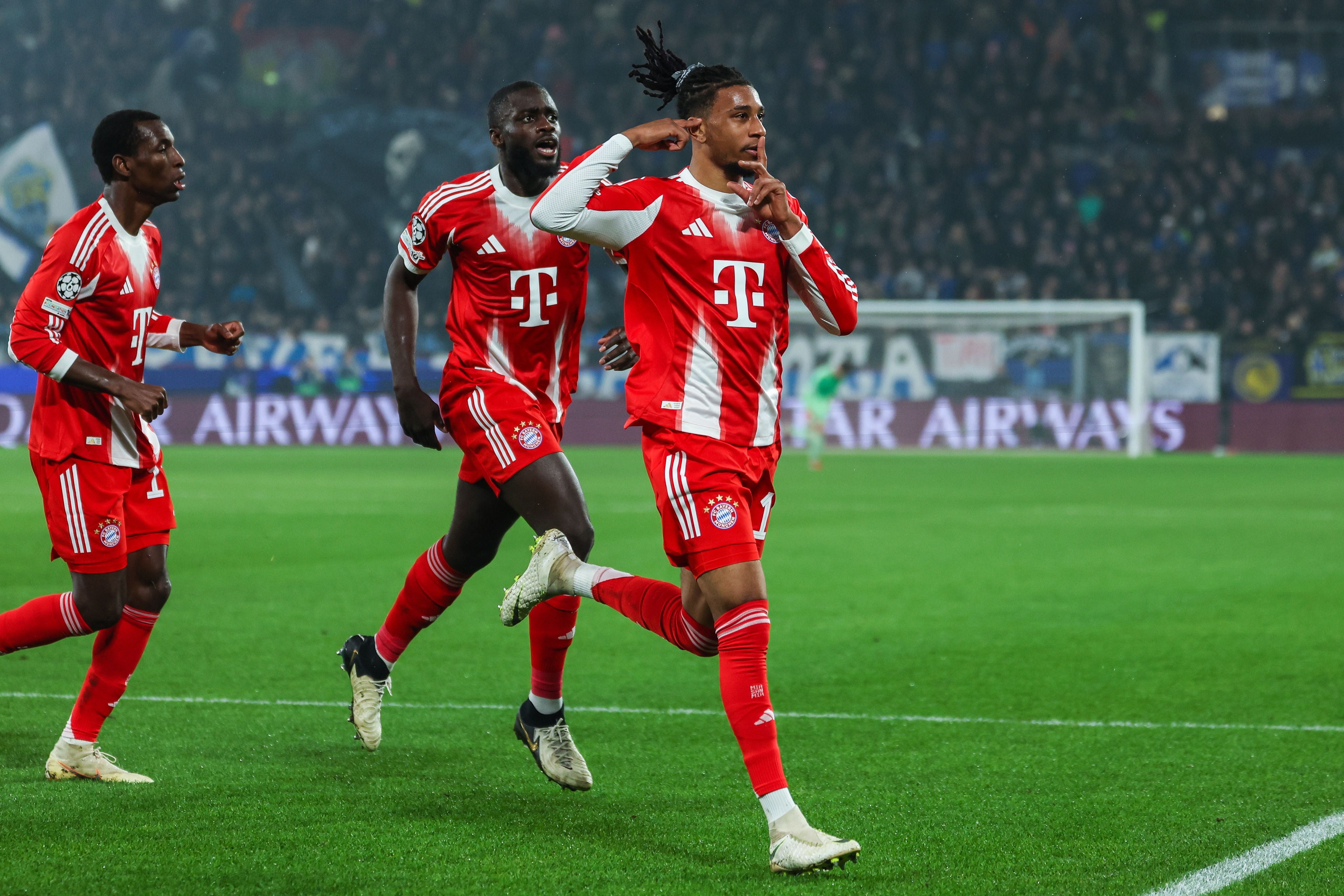 Drei Bayern-Spieler feiern ein Tor während eines Champions-League-Spiels im Stadion.