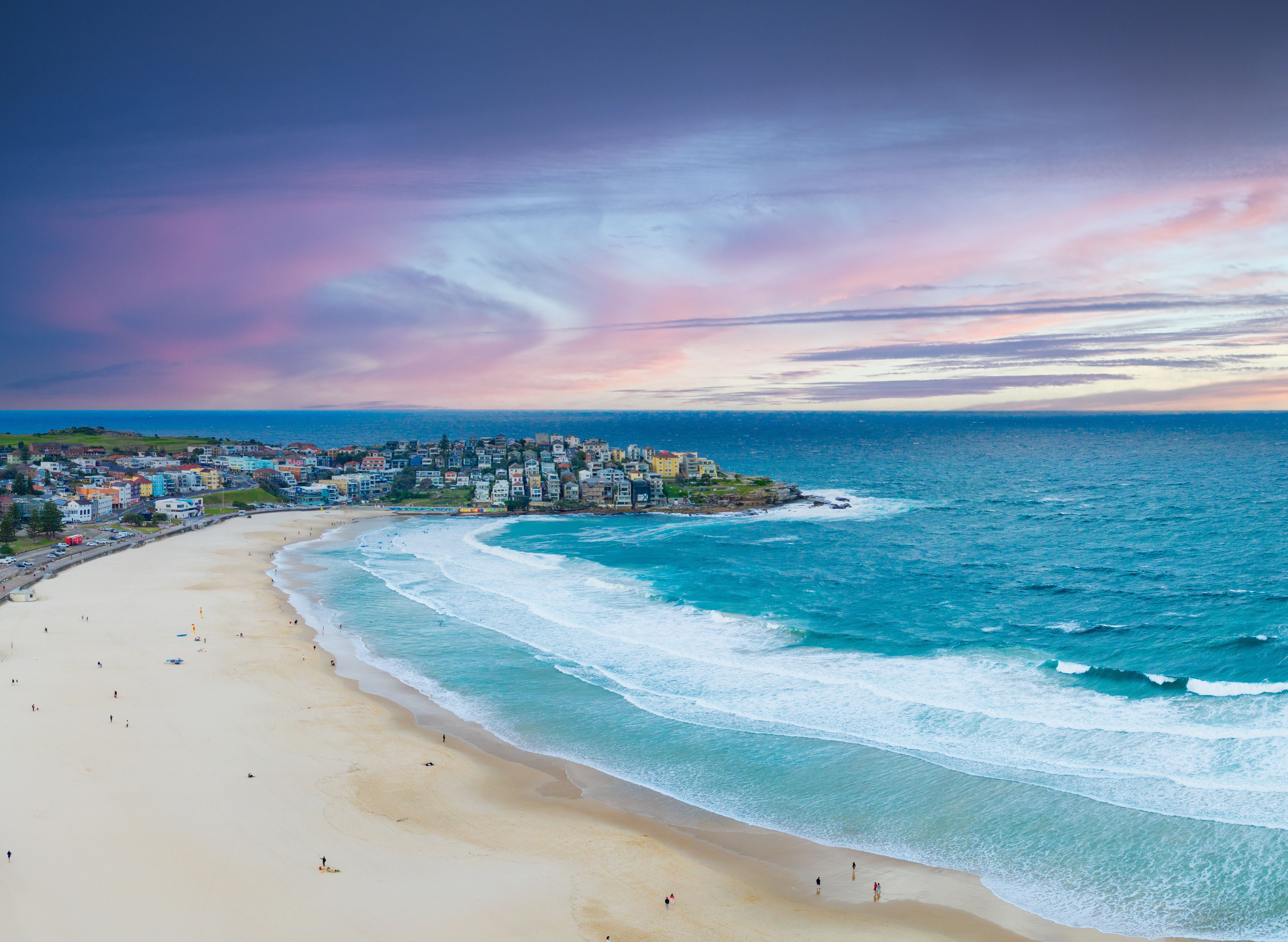 Aerial-Aufnahme vom Bondi Beach in Sydney mit Menschen am Strand und dramatischem Himmel.