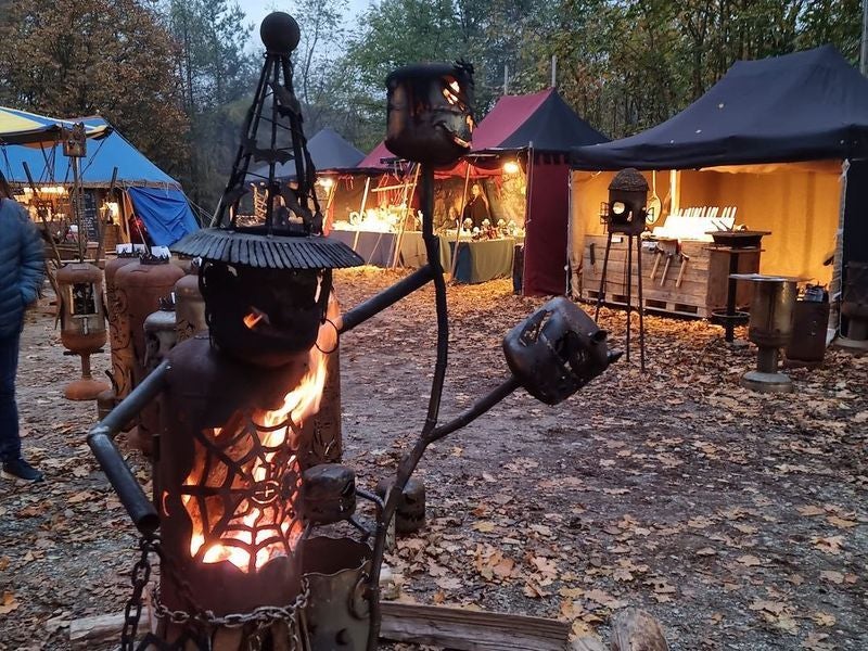 Metallskulpturen mit Feuer vor bunten Marktständen auf den Markttagen bei der Burgruine Aggstein.