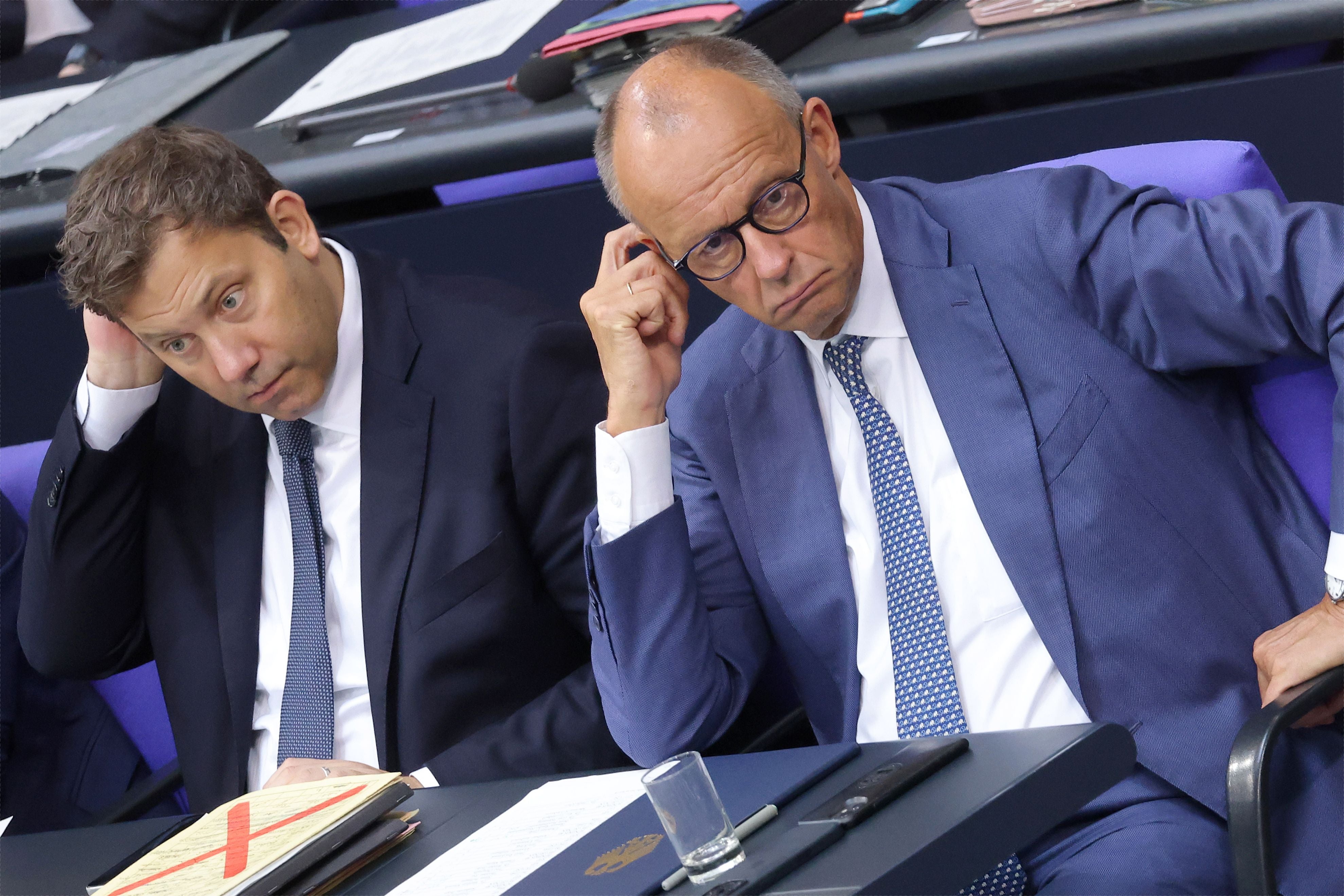 Zwei Männer im Anzug sitzen nachdenklich während einer Debatte im Bundestag.