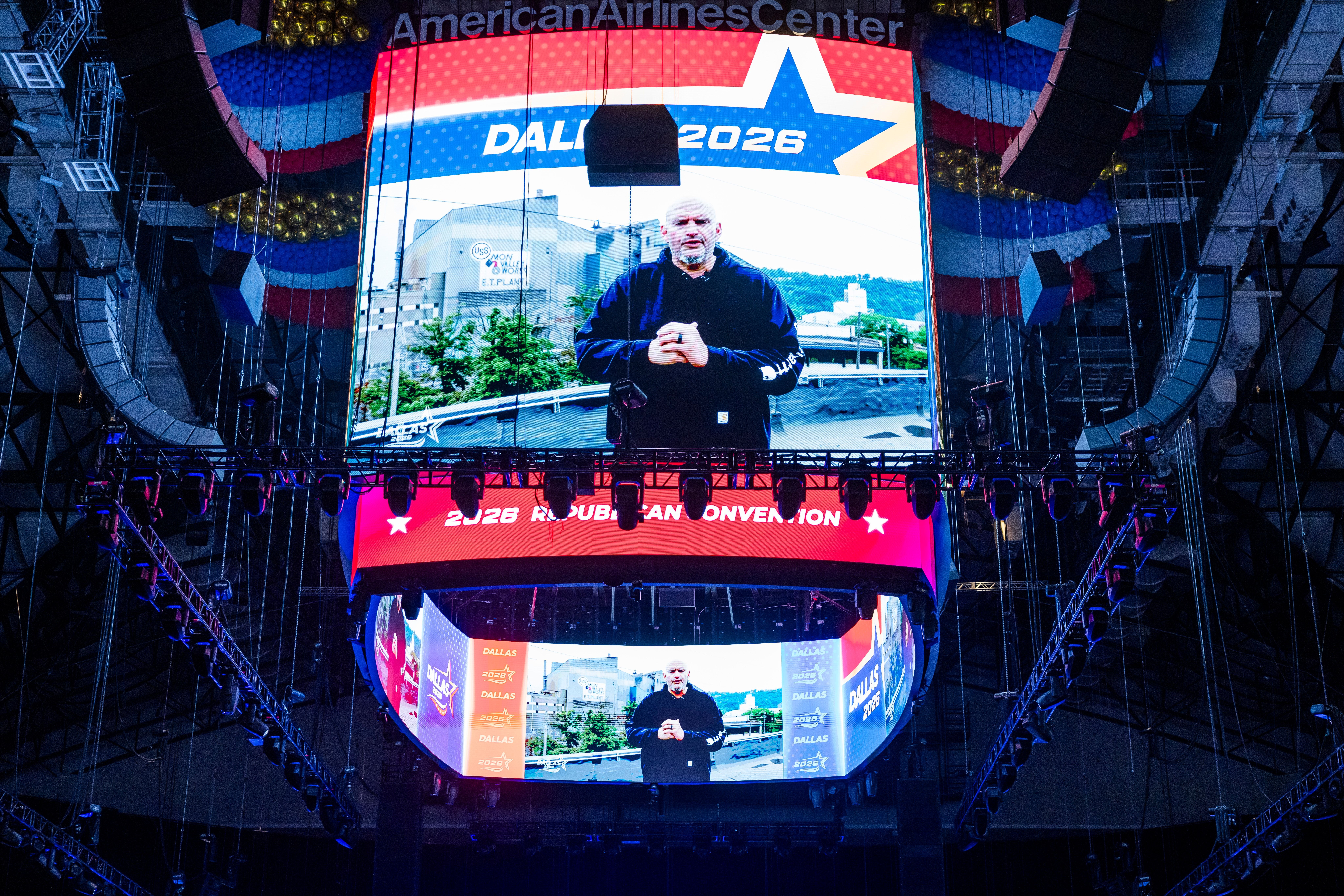 Ein großer Bildschirm zeigt einen Mann vor der Aufschrift „Dallas 2026“ in einer Arena.