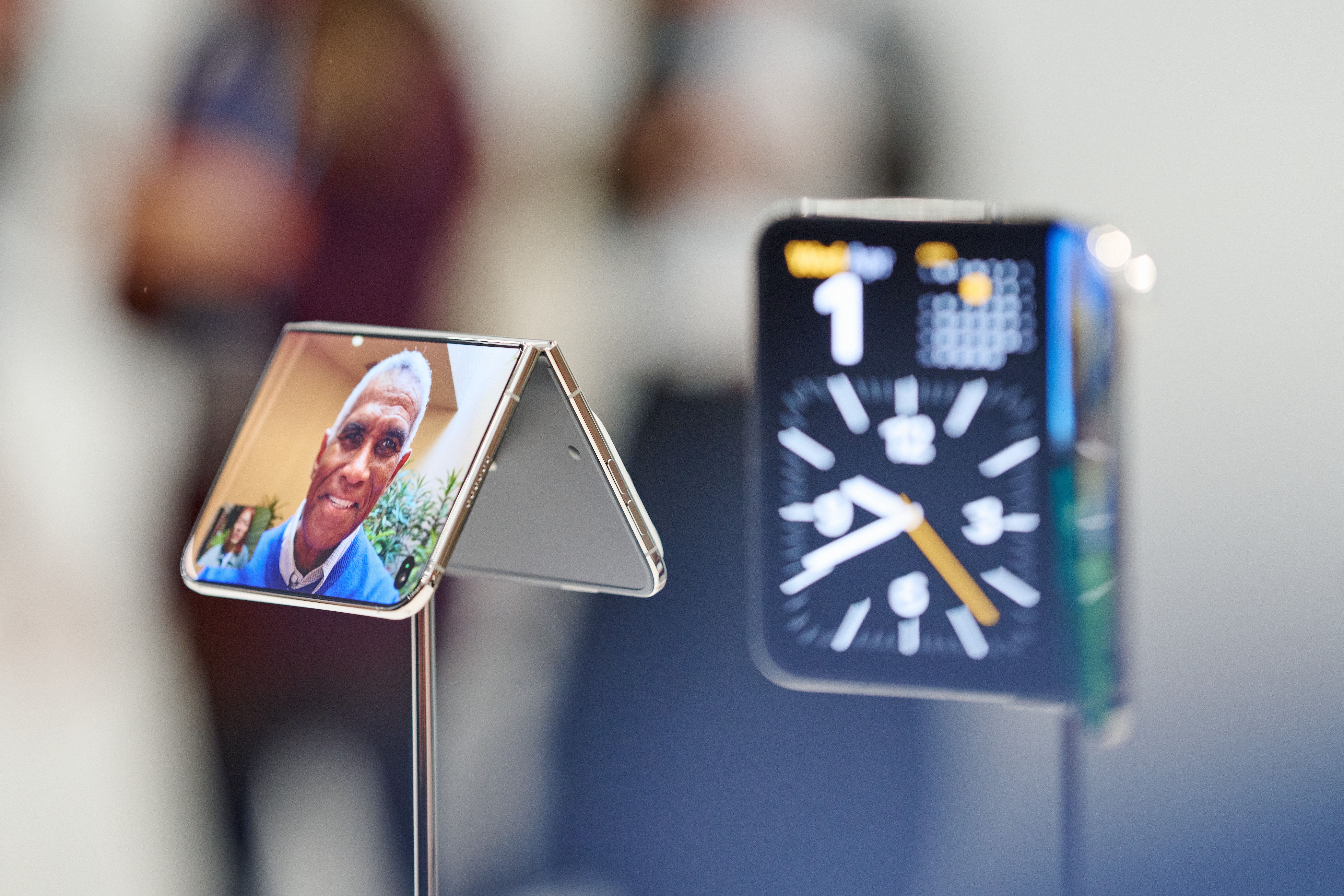 Zwei Apple-Geräte: ein aufgestelltes faltbares iPhone mit Videoanruf und eine Smartwatch.