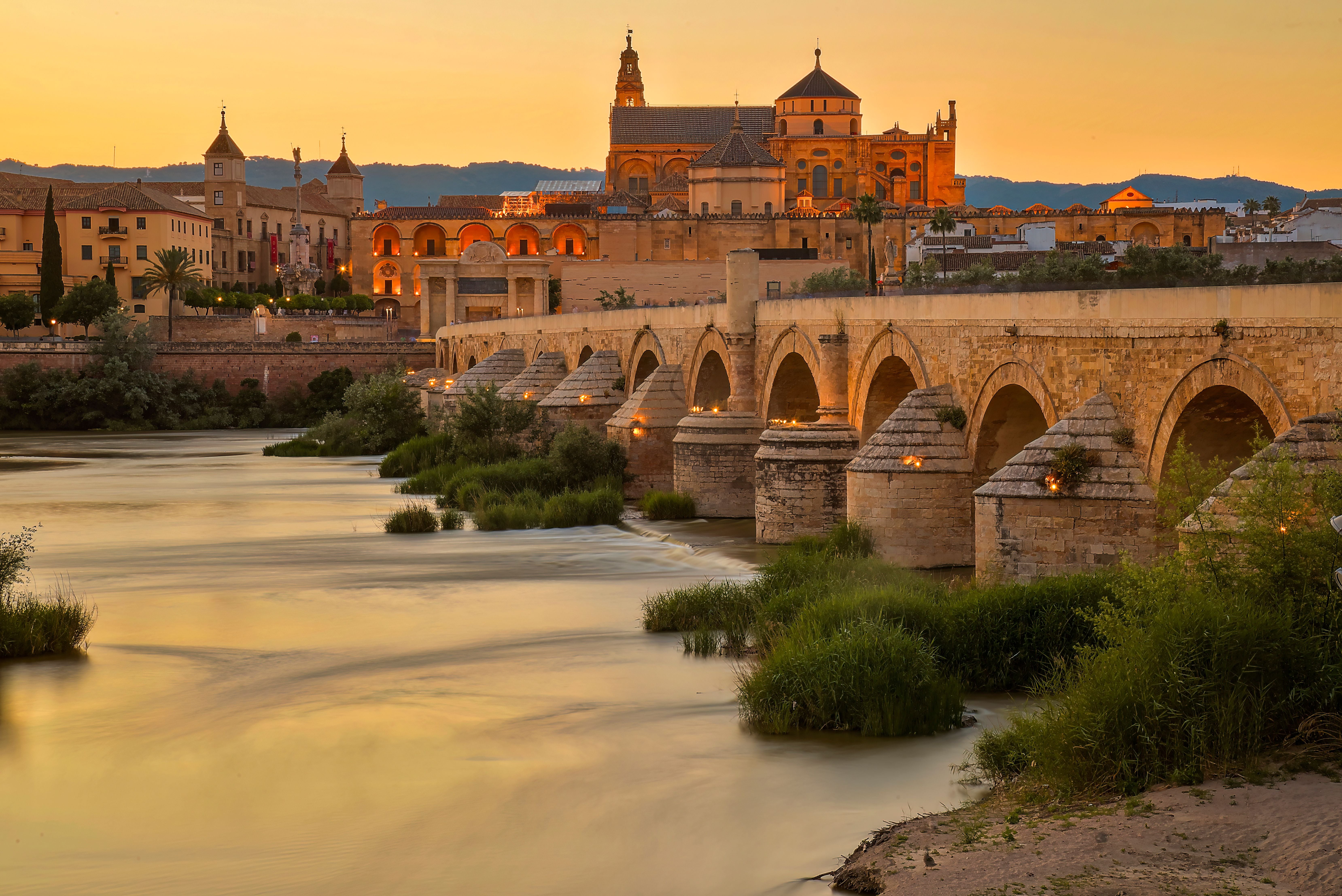 Blick auf die Altstadt von Córdoba und die Römische Brücke bei Sonnenuntergang am Fluss Guadalquivir.