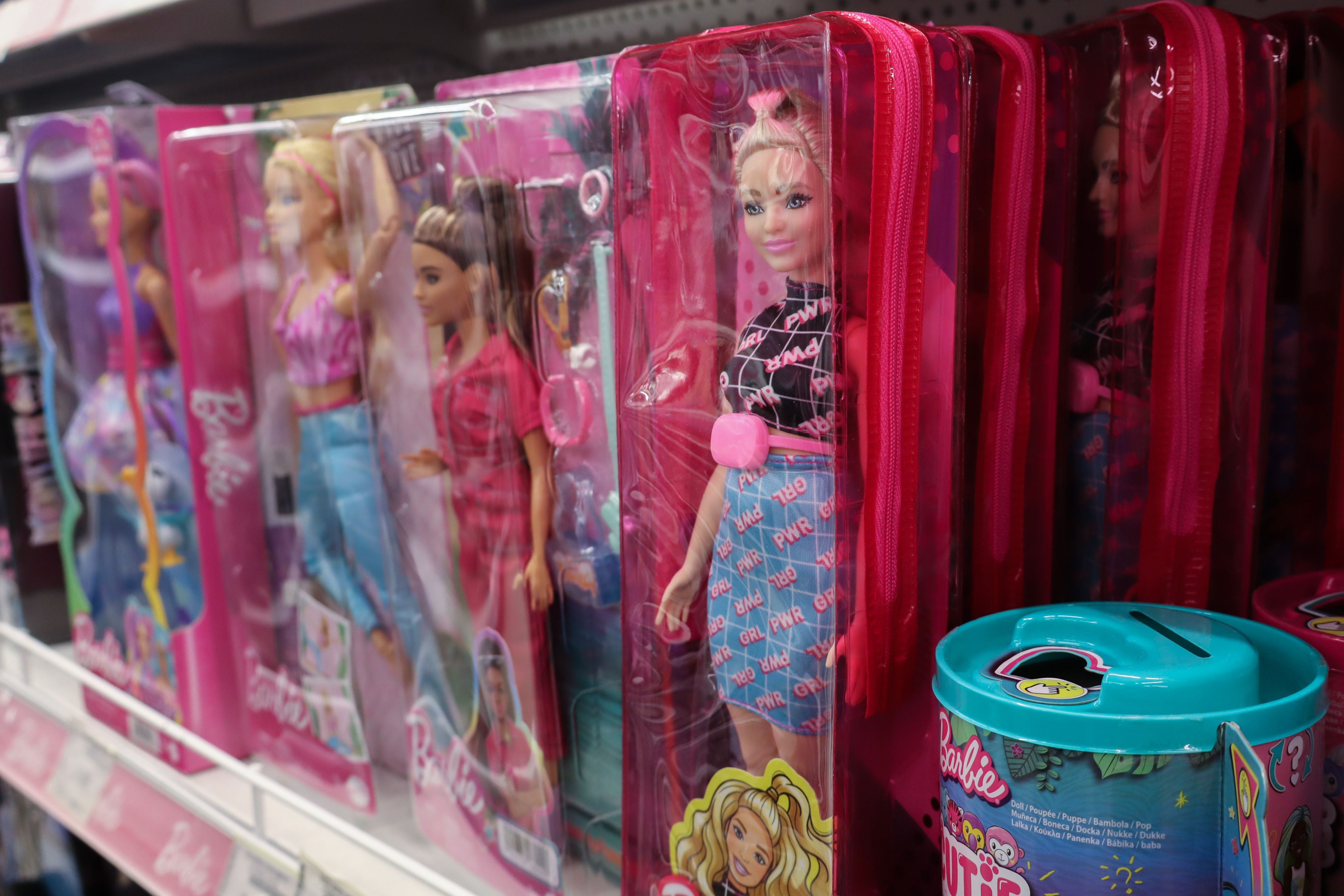 Barbiepuppen in bunten Kunststoffverpackungen stehen nebeneinander im Regal eines Spielzeugladens.