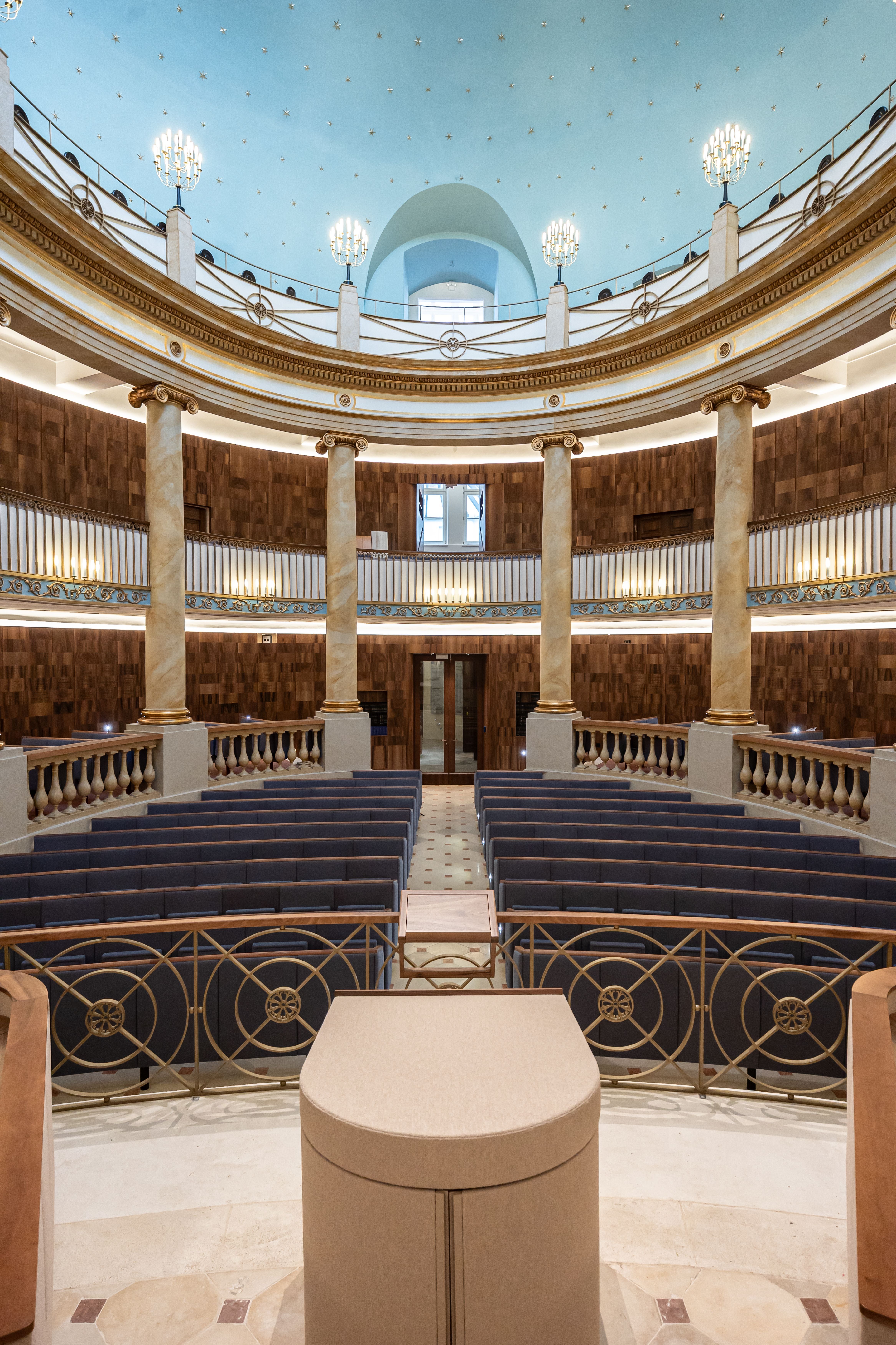 Innenansicht des sanierten jüdischen Stadttempels in Wien mit Sitzreihen und blauer Kuppel.