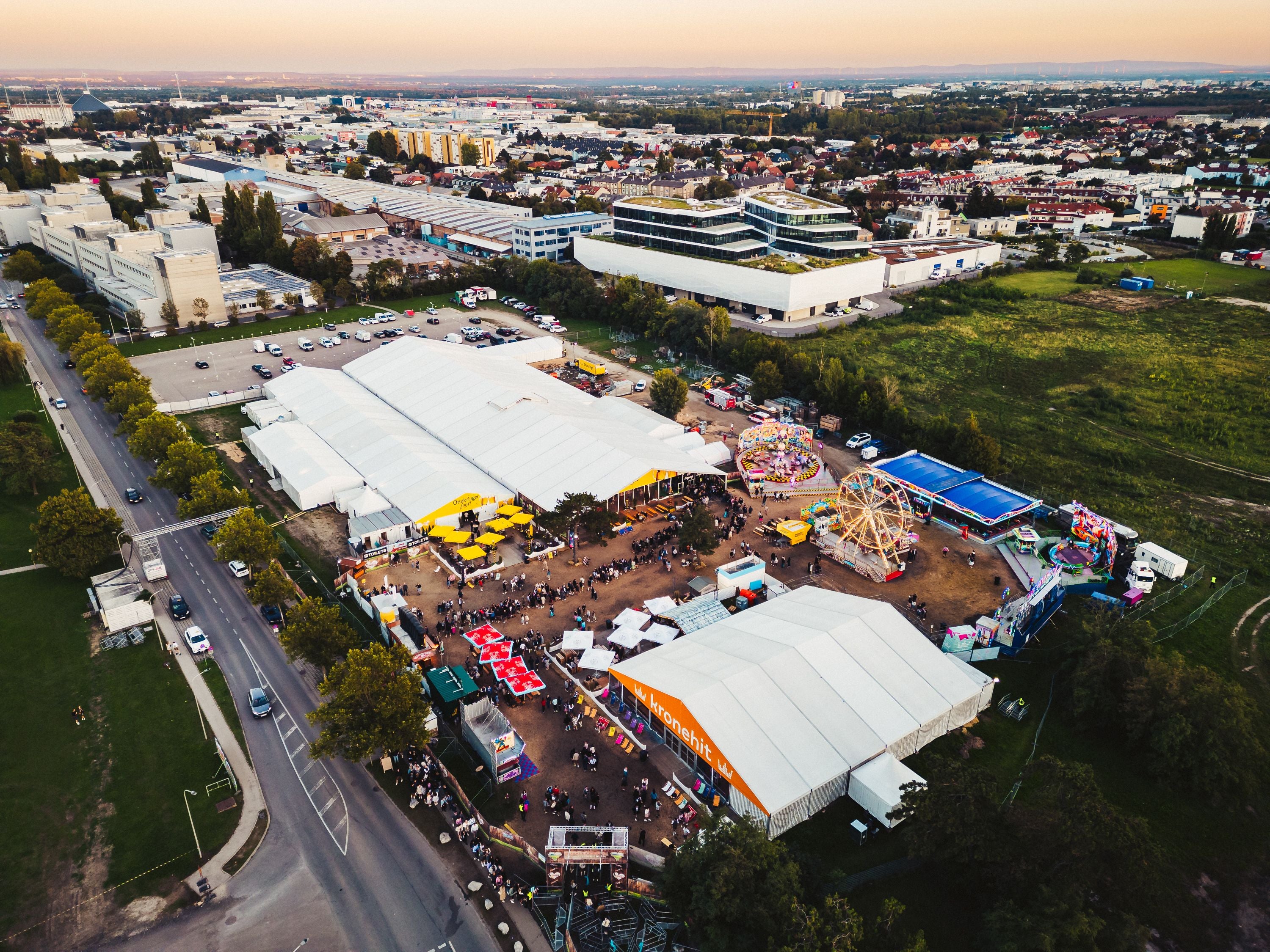 Luftaufnahme eines Volksfestes mit Festzelten, Fahrgeschäften und Menschen auf dem Brunner Wiesn.