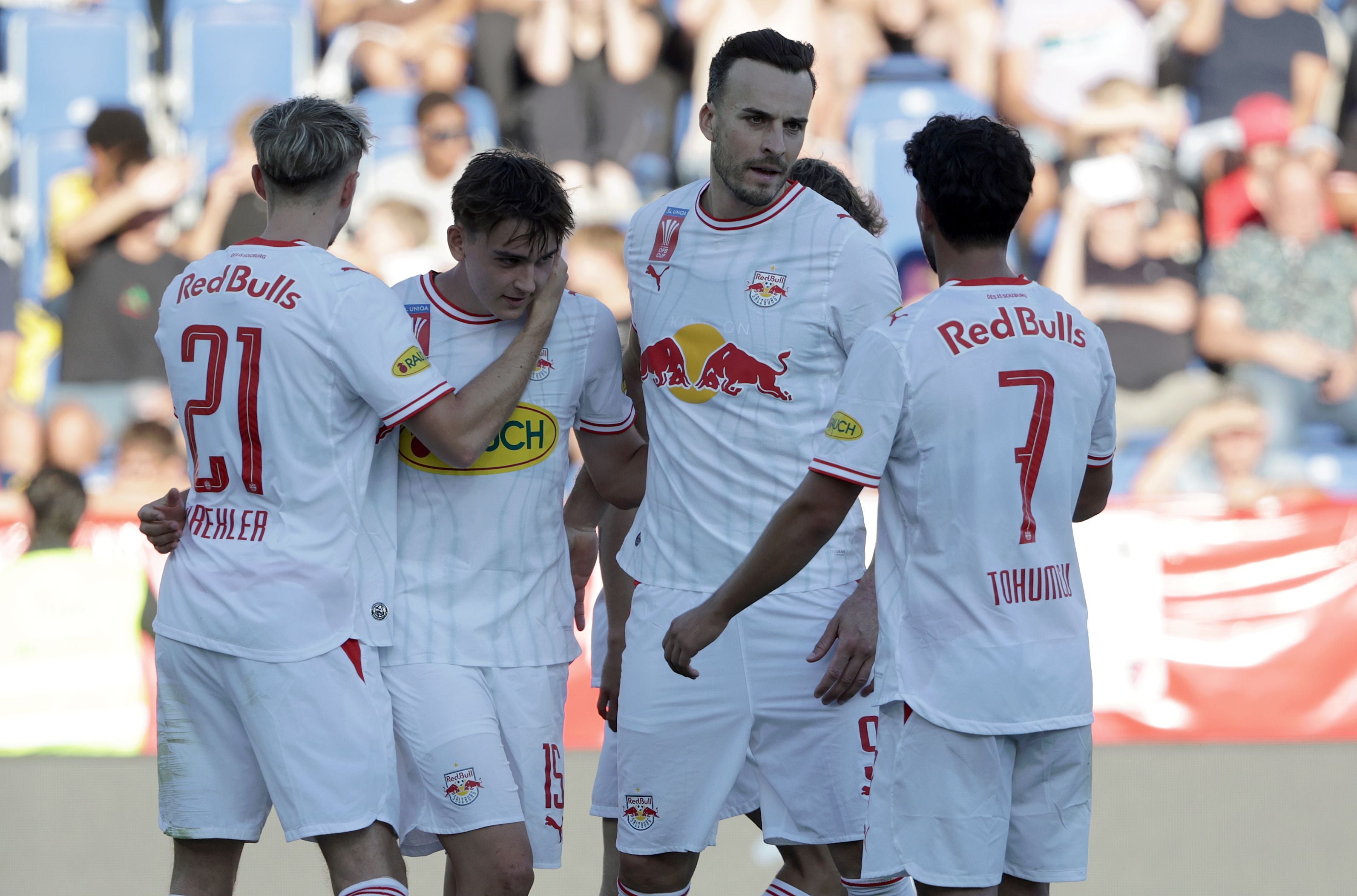 Vier Fußballspieler von Red Bull Salzburg jubeln gemeinsam auf dem Spielfeld.