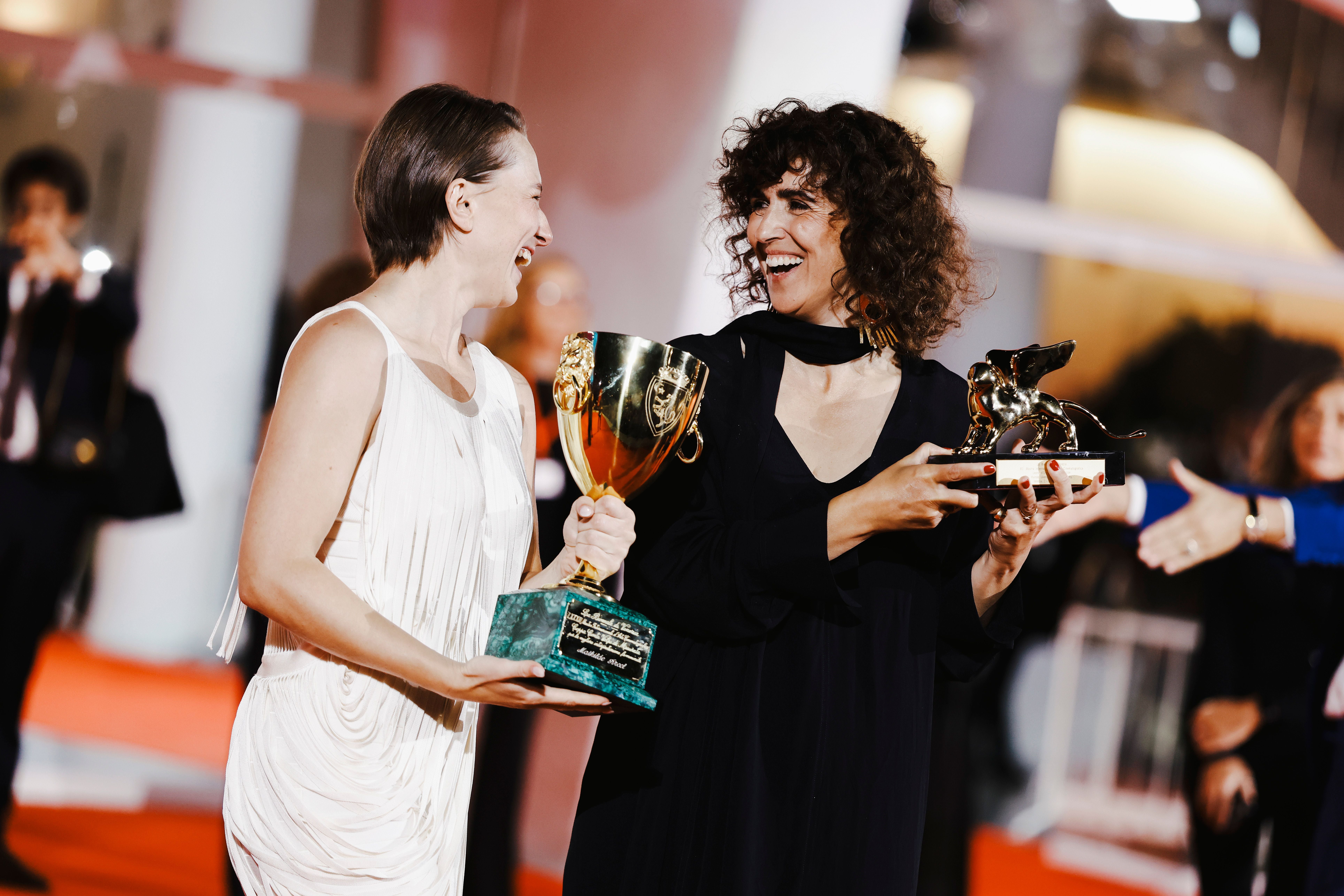Zwei Frauen halten lachend Filmpreise bei einer Preisverleihung in Venedig.