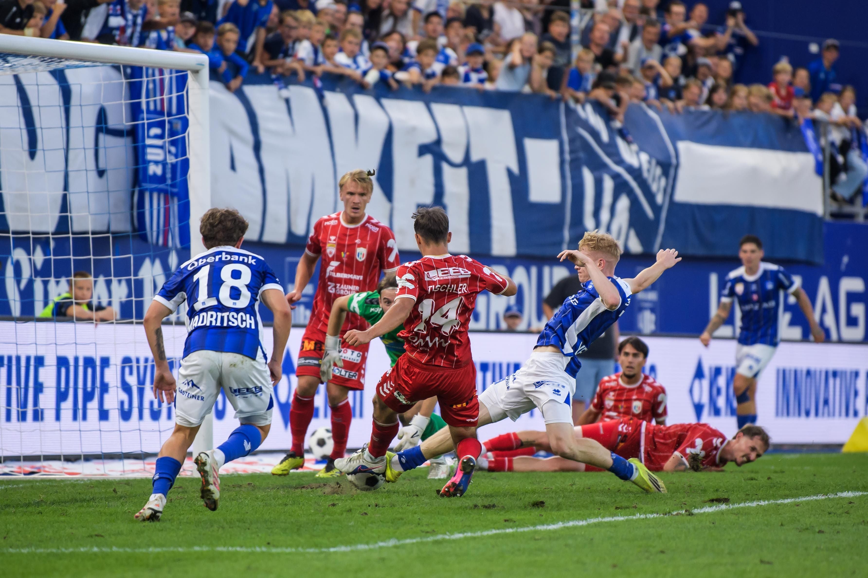 Fussballspiel zwischen Blau Weiss Linz und Hertha Wels vor jubelnden Zuschauern im Stadion.