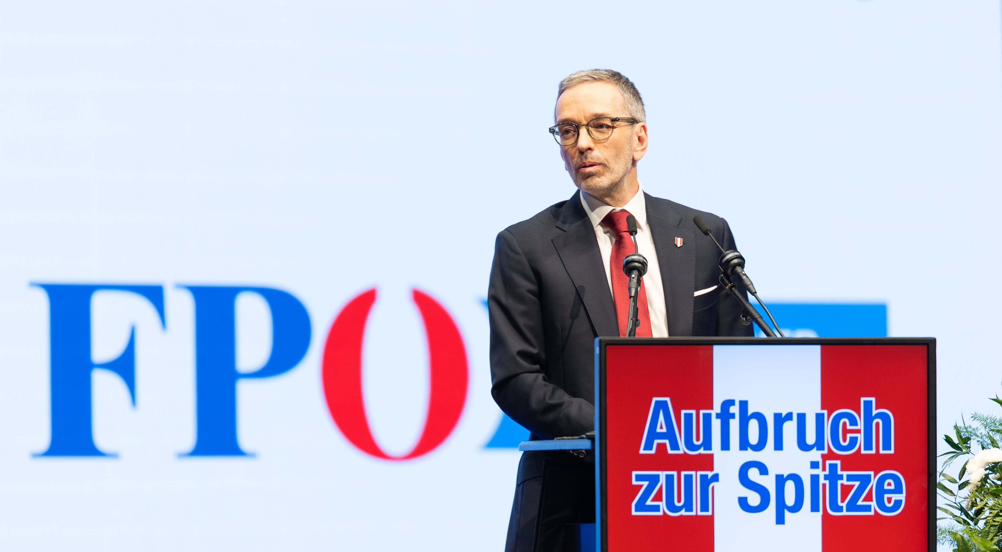 Ein Mann im Anzug spricht am Rednerpult mit der Aufschrift „Aufbruch zur Spitze“.