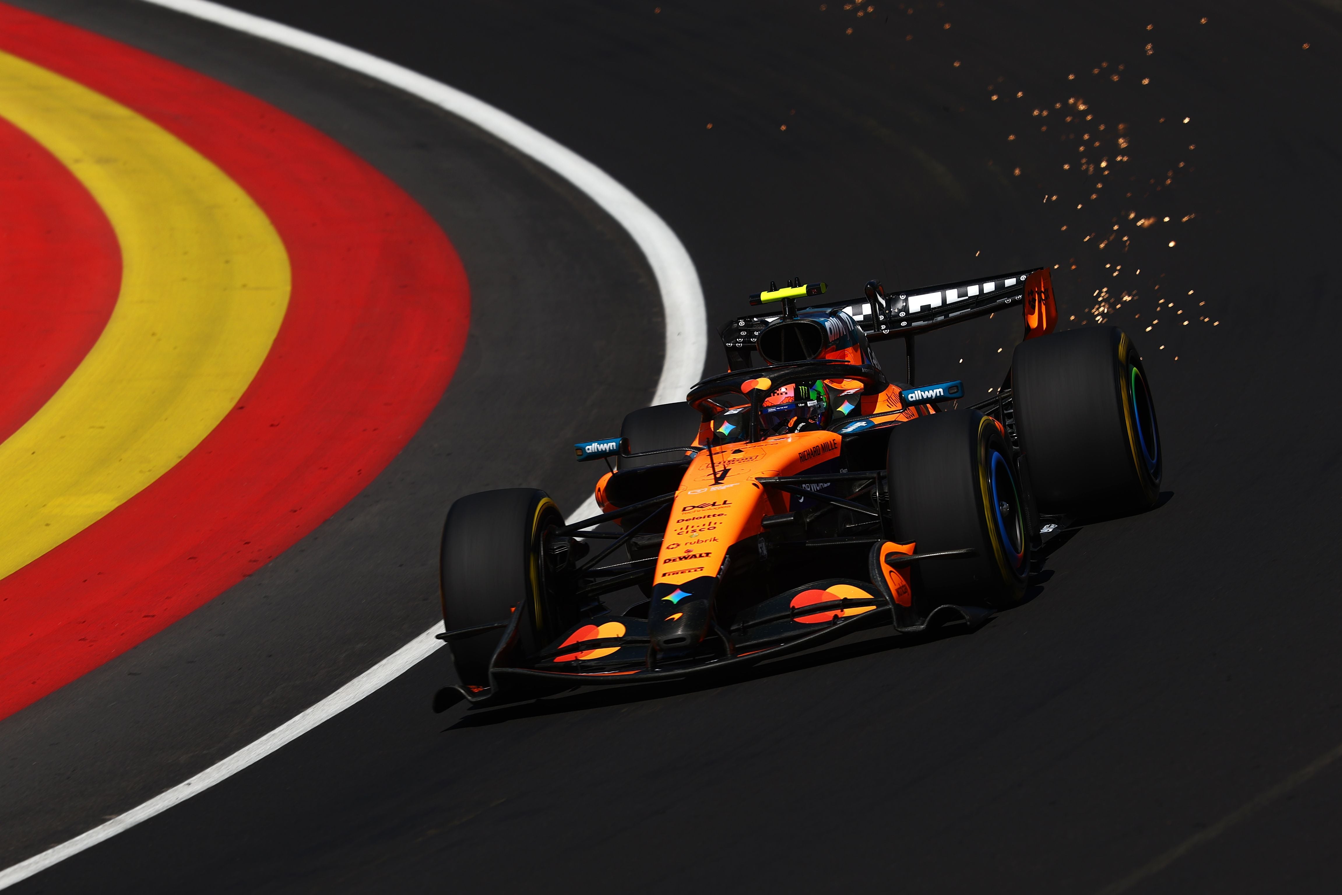 Ein orangefarbener Formel-1-Wagen fährt mit Funkenflug durch eine Kurve auf der Rennstrecke.