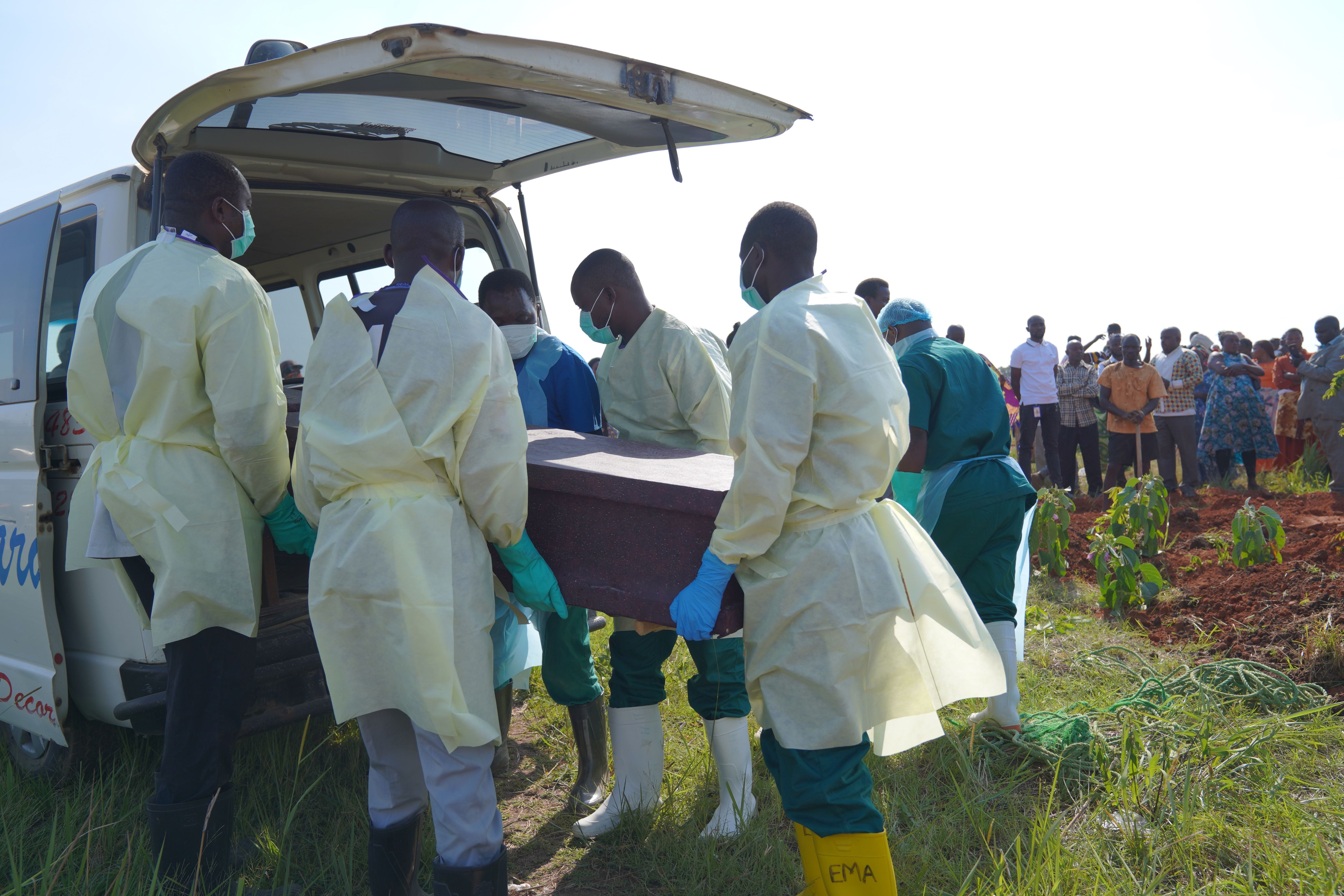 Gesundheitsarbeiter tragen einen Sarg bei einer Beerdigung für Ebola-Opfer im Freien.