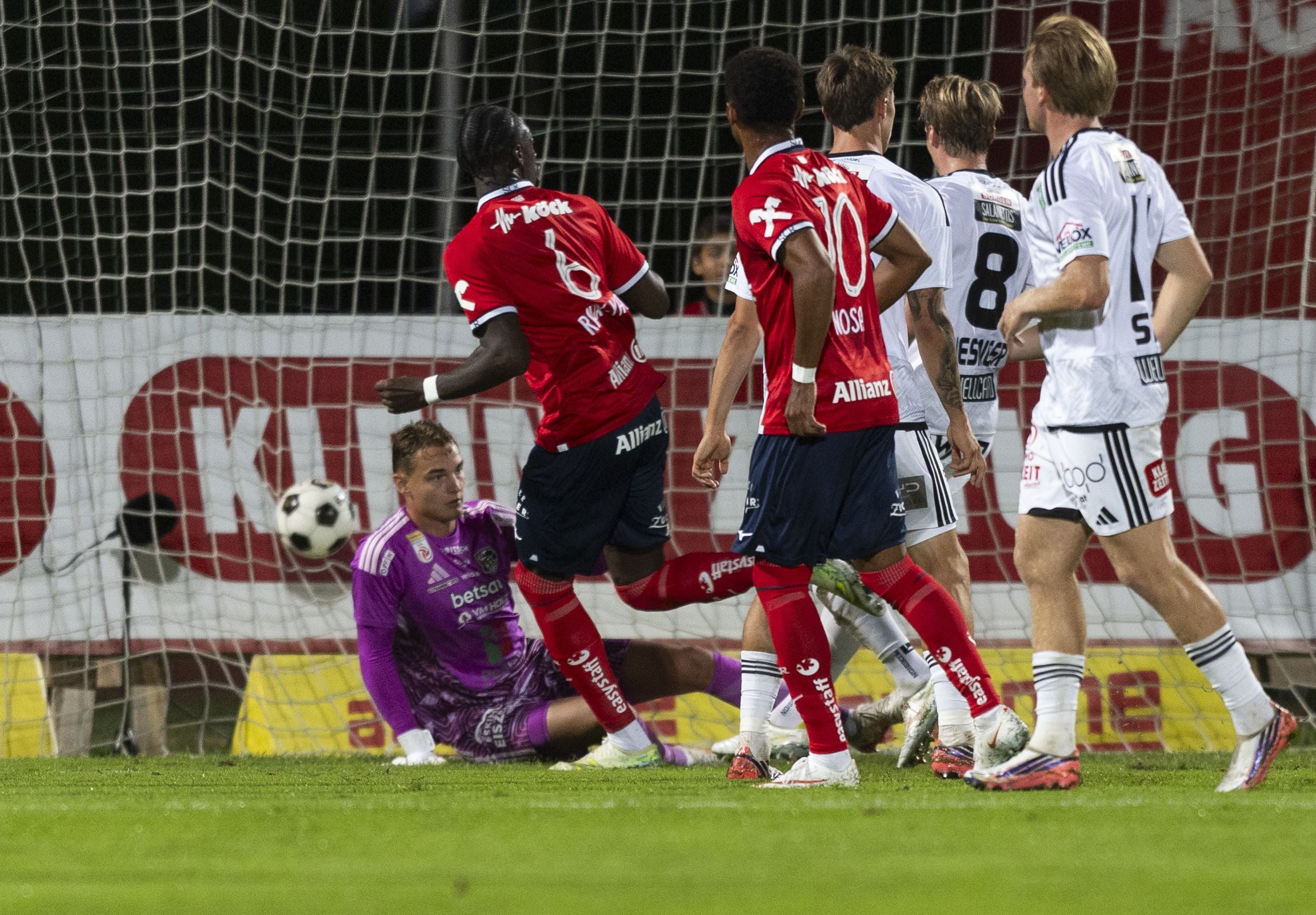 Ein Fußballspiel, Spieler kämpfen vor dem Tor und der Torwart versucht, den Ball zu halten.