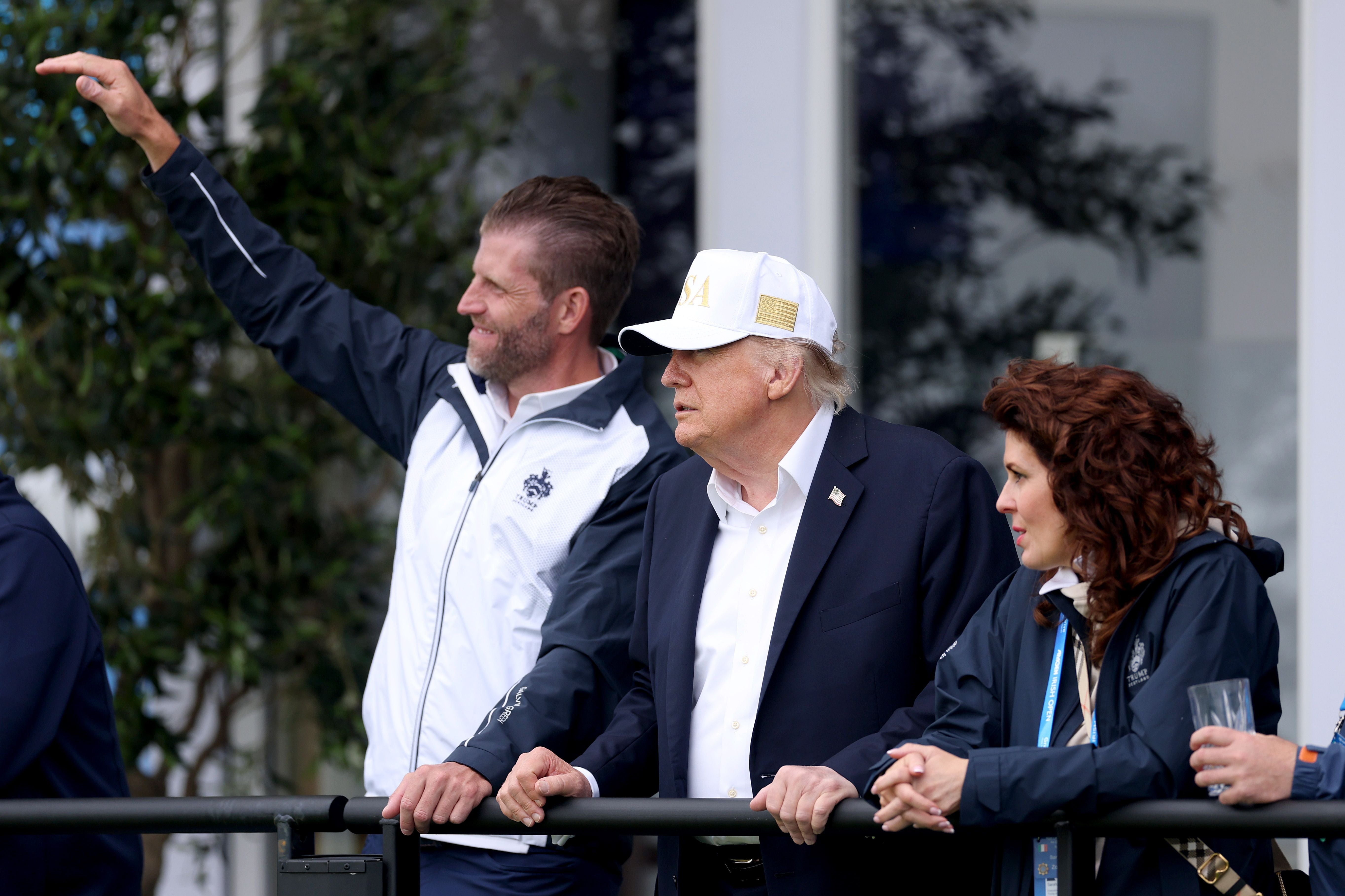 Drei Personen stehen draußen an einem Geländer und blicken in die Ferne.