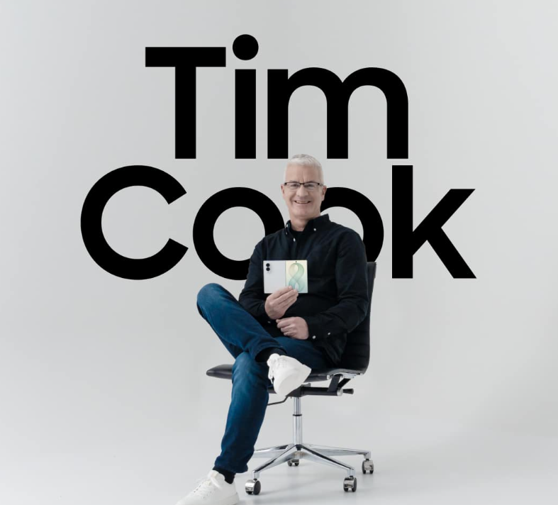 Ein Mann sitzt auf einem Stuhl und hält ein Smartphone, hinter ihm steht groß "Tim Cook".