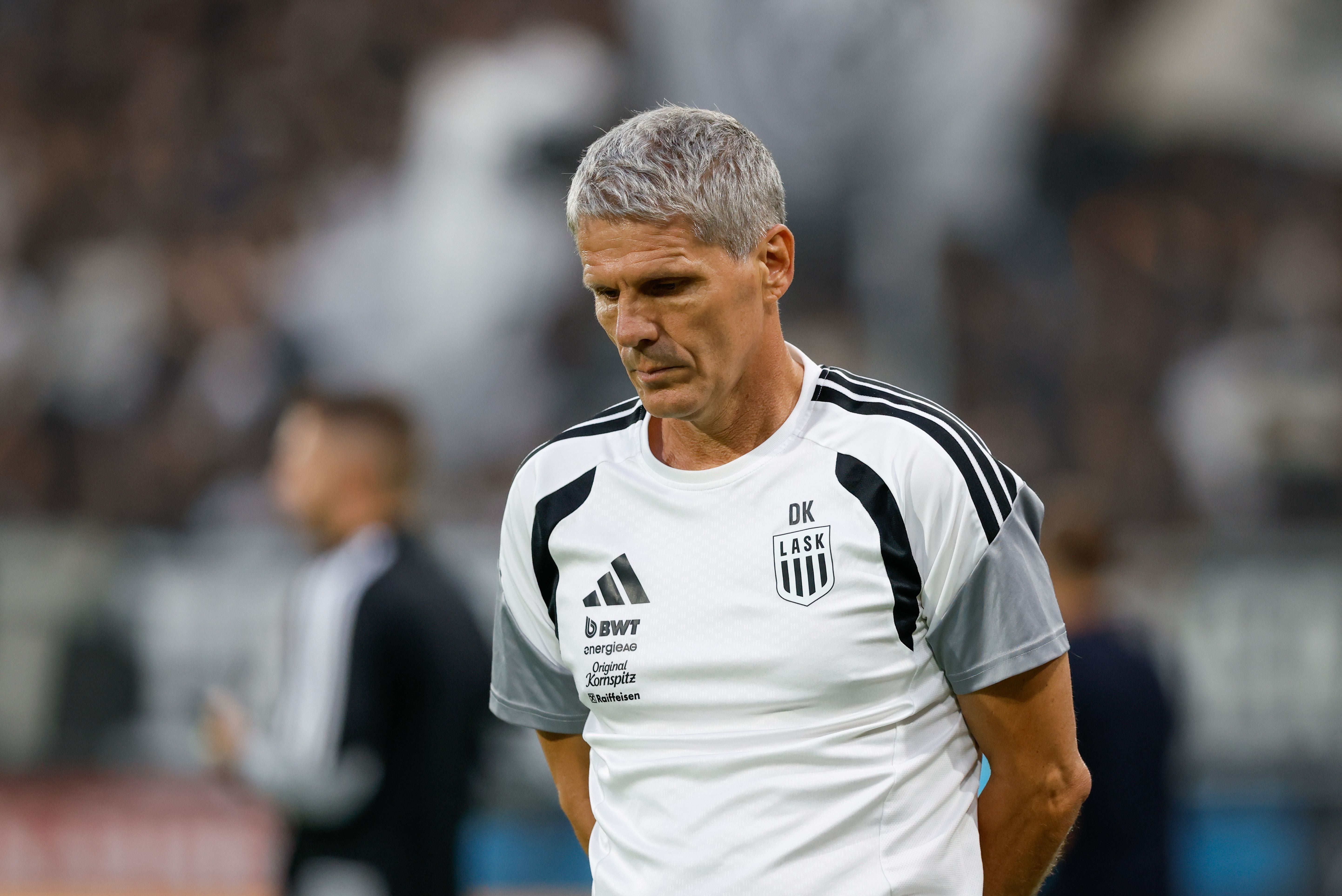 Ein enttäuschter Trainer von LASK mit verschränkten Armen auf dem Spielfeld.
