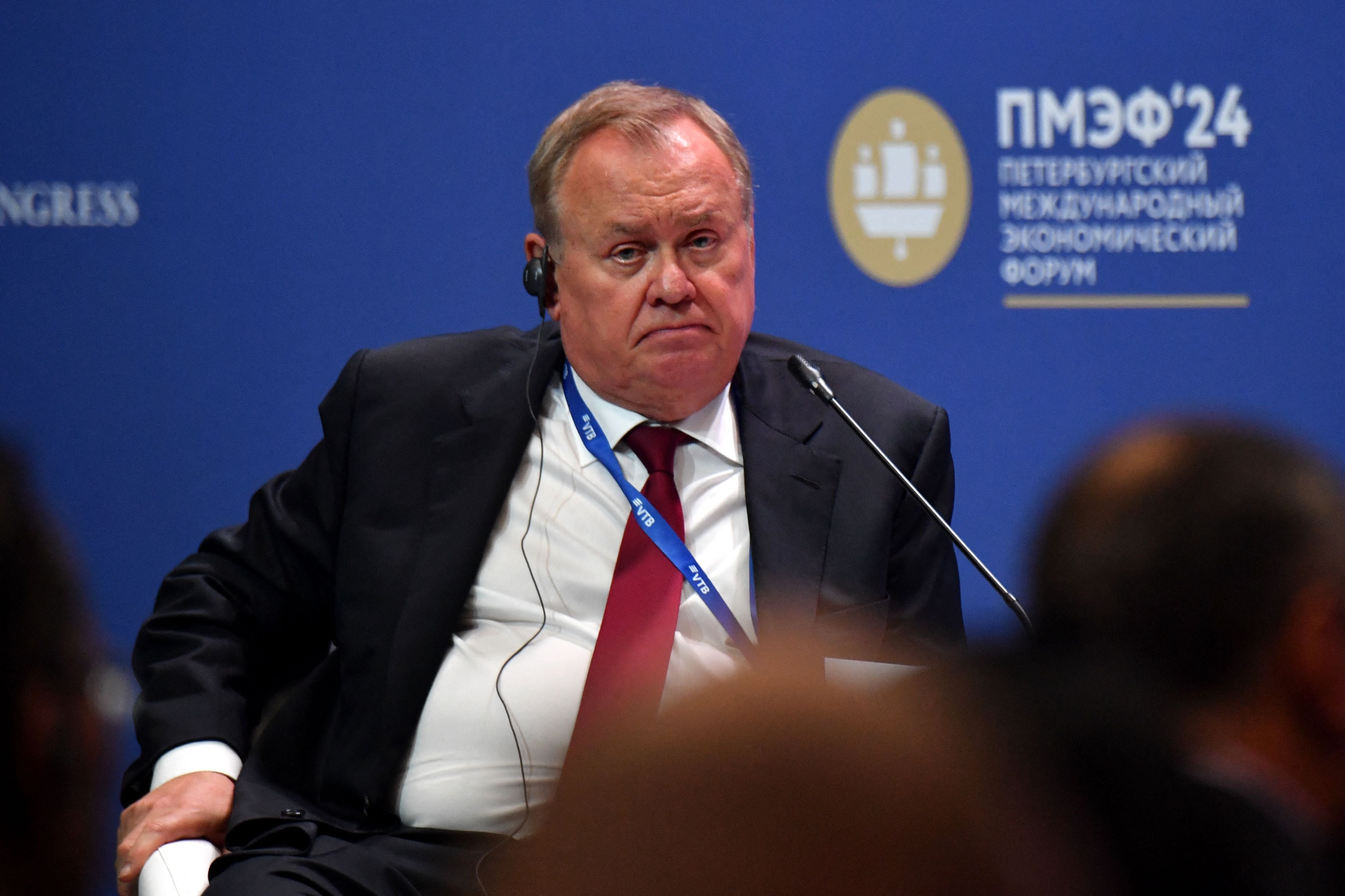 Mann im Anzug mit Headset sitzt auf Podium beim Sankt Petersburger Wirtschaftsforum 2024.