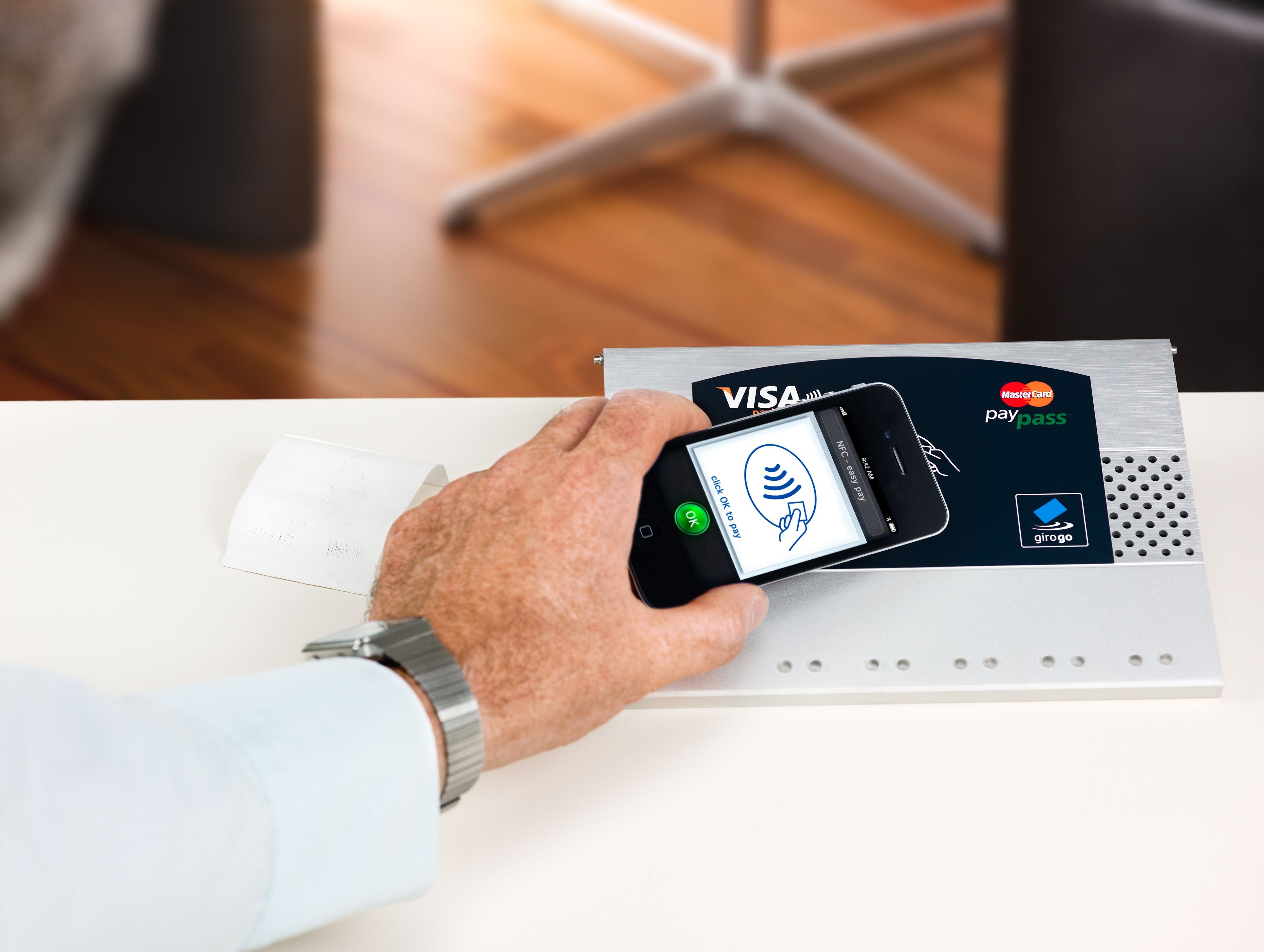 Eine Person zahlt mit einem iPhone per NFC an einem kontaktlosen Terminal.