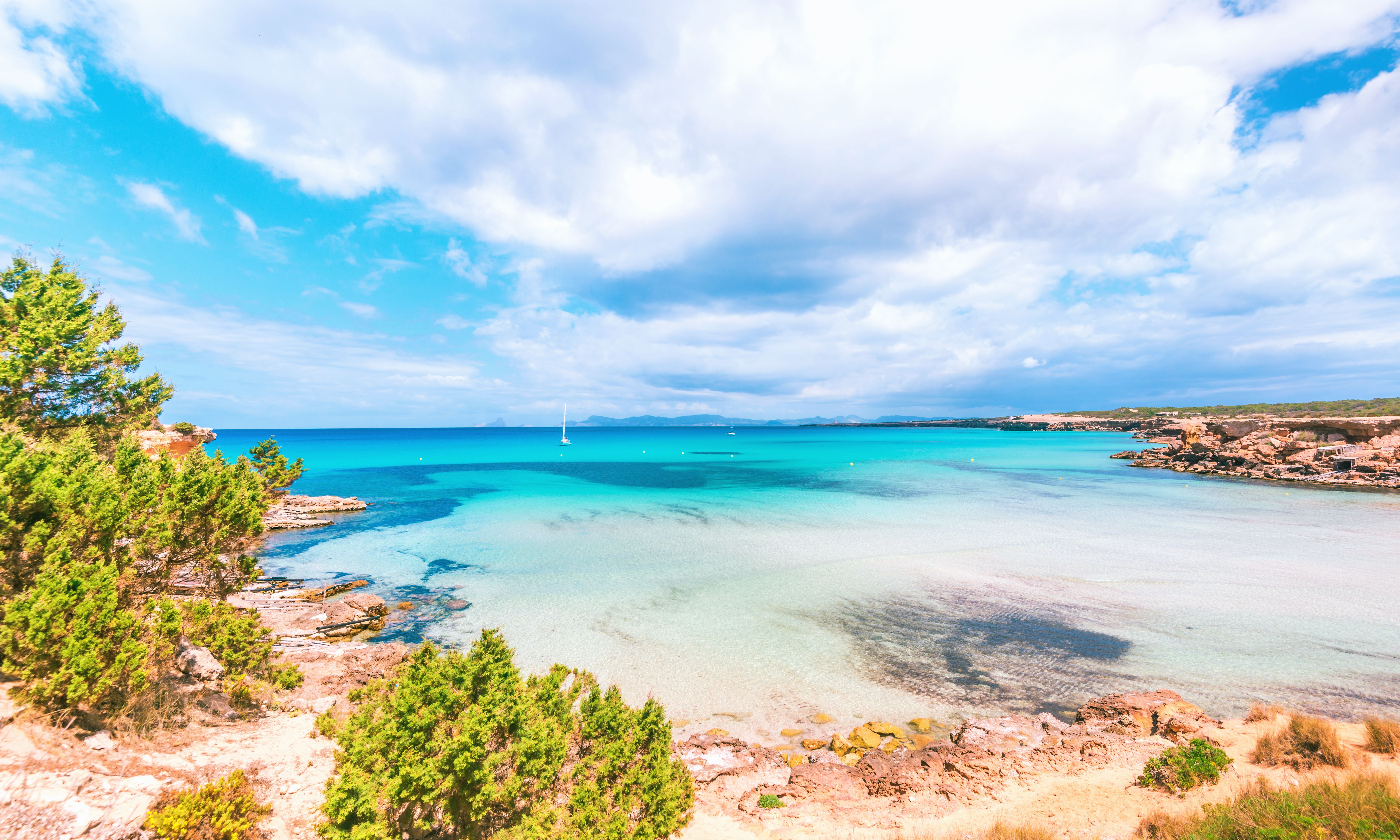 Blick auf die Bucht Cala Saona auf Formentera mit türkisblauem Wasser und Segelbooten.