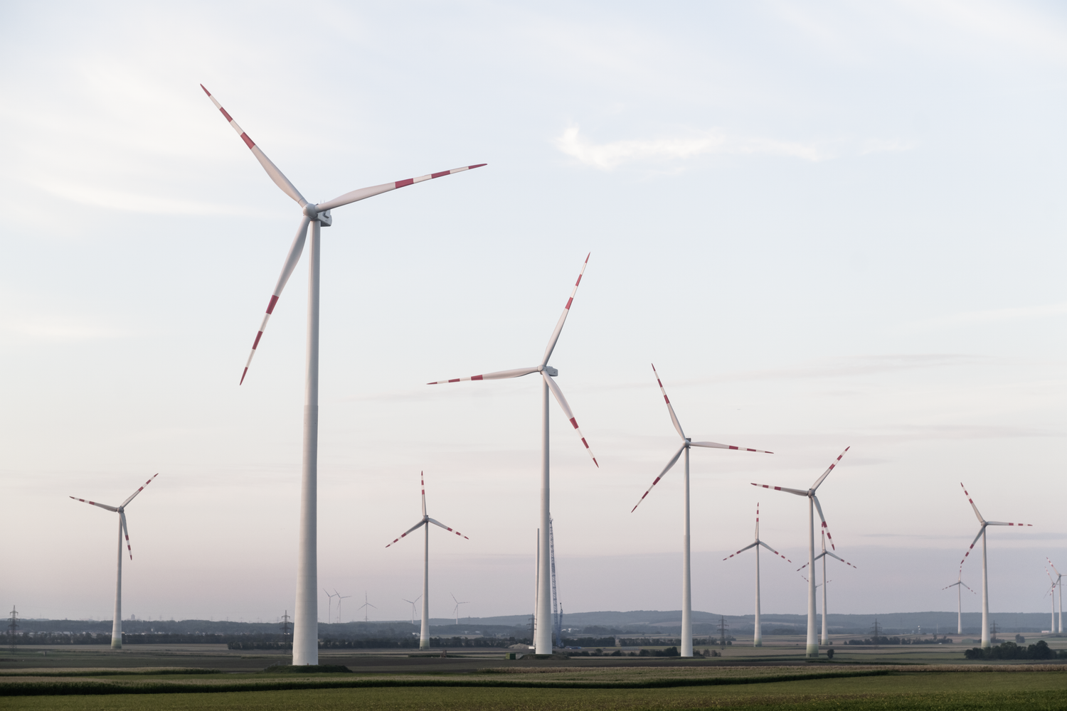 Mehrere Windräder stehen auf einem Feld unter bewölktem Himmel bei Tageslicht.