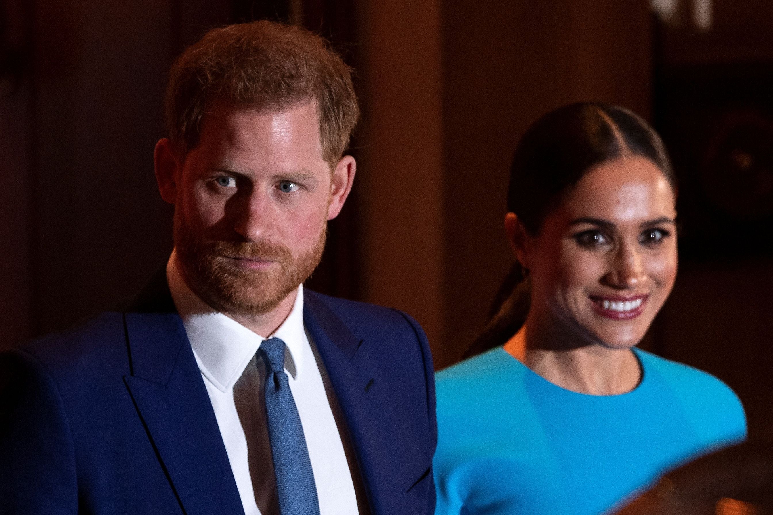 Ein Mann im blauen Anzug und eine Frau im blauen Kleid stehen nebeneinander und lächeln.
