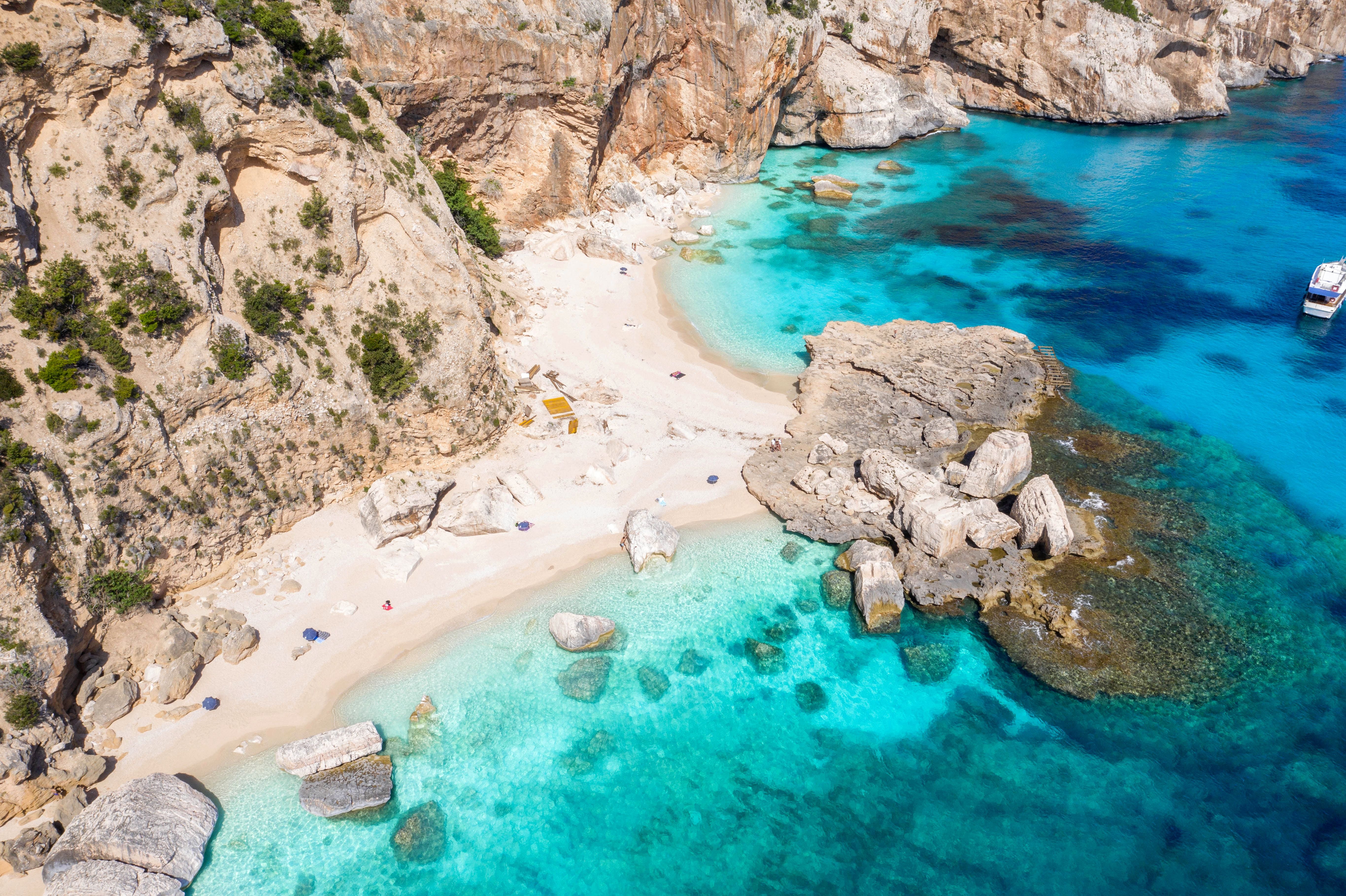 Luftaufnahme des Strandes Cala Mariolu mit türkisblauem Wasser und Felsen in Sardinien.