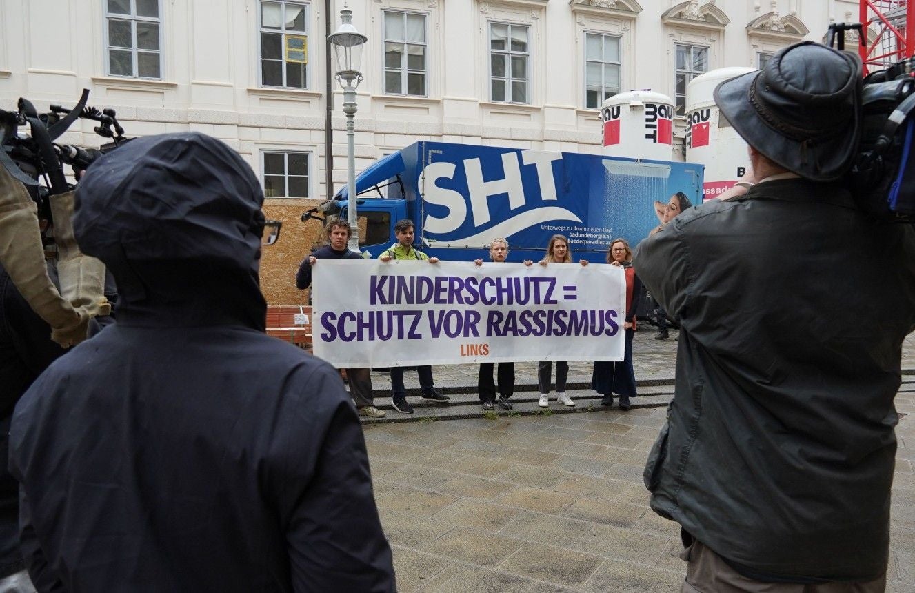 Menschen halten ein Banner mit der Aufschrift „Kinderschutz = Schutz vor Rassismus“ bei einer Demo.