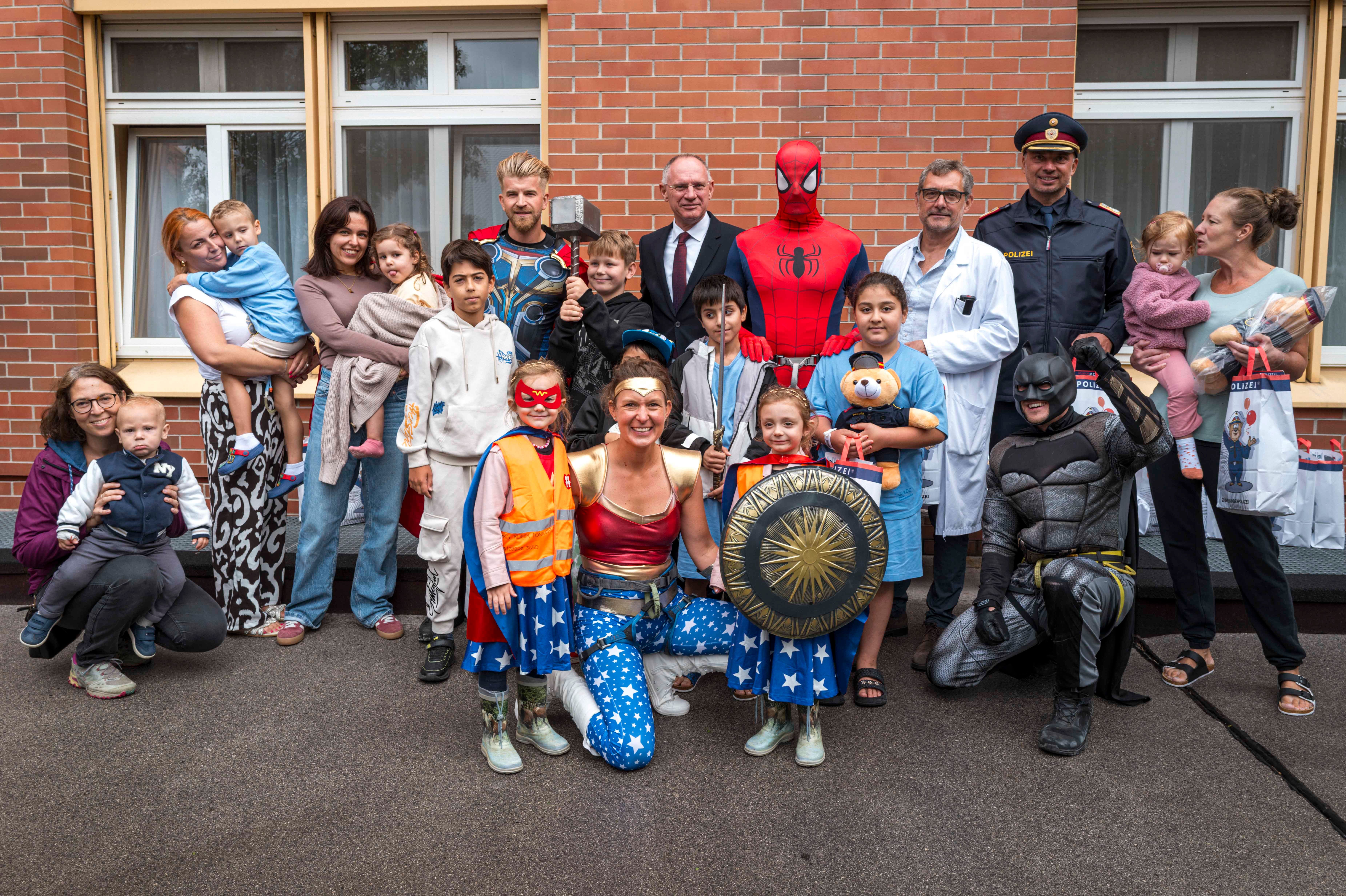 Gruppe von Kindern und Erwachsenen, einige als Superhelden wie Batman und Spider-Man verkleidet.