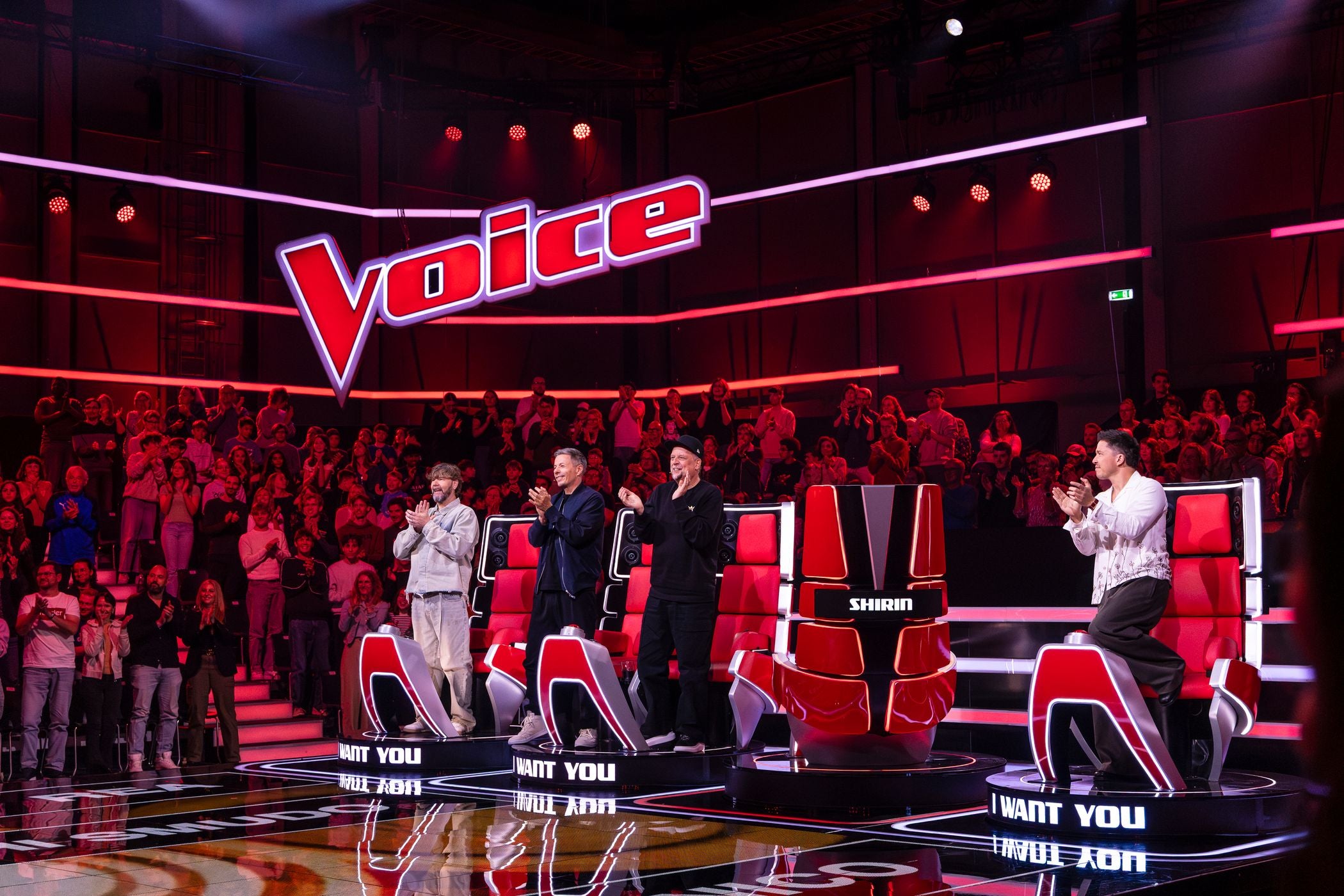 Vier Coaches stehen und applaudieren bei "The Voice of Germany" vor großem, jubelndem Publikum.