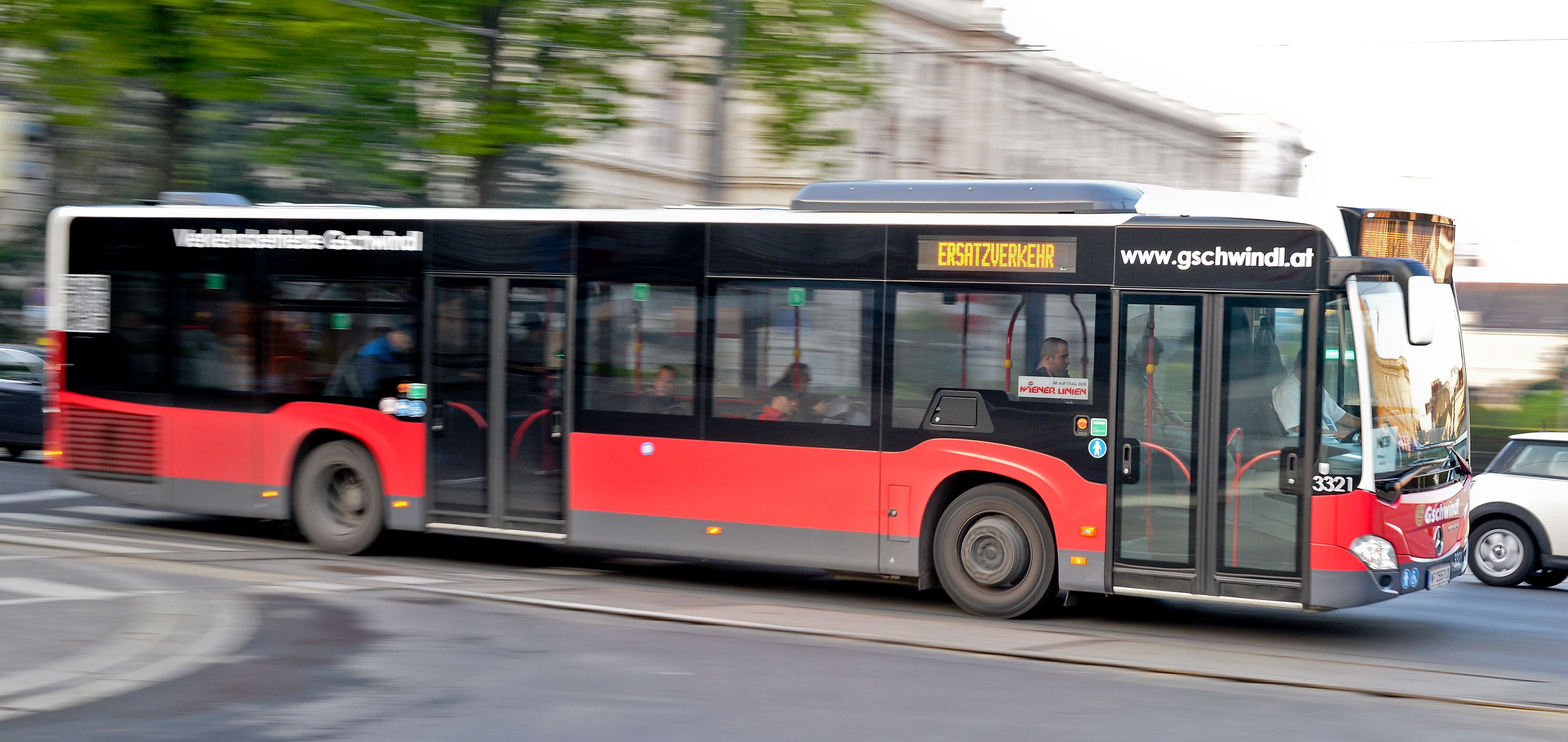 Roter Ersatzverkehr-Bus fährt auf der Ringstraße in Wien, Menschen sitzen im Inneren.