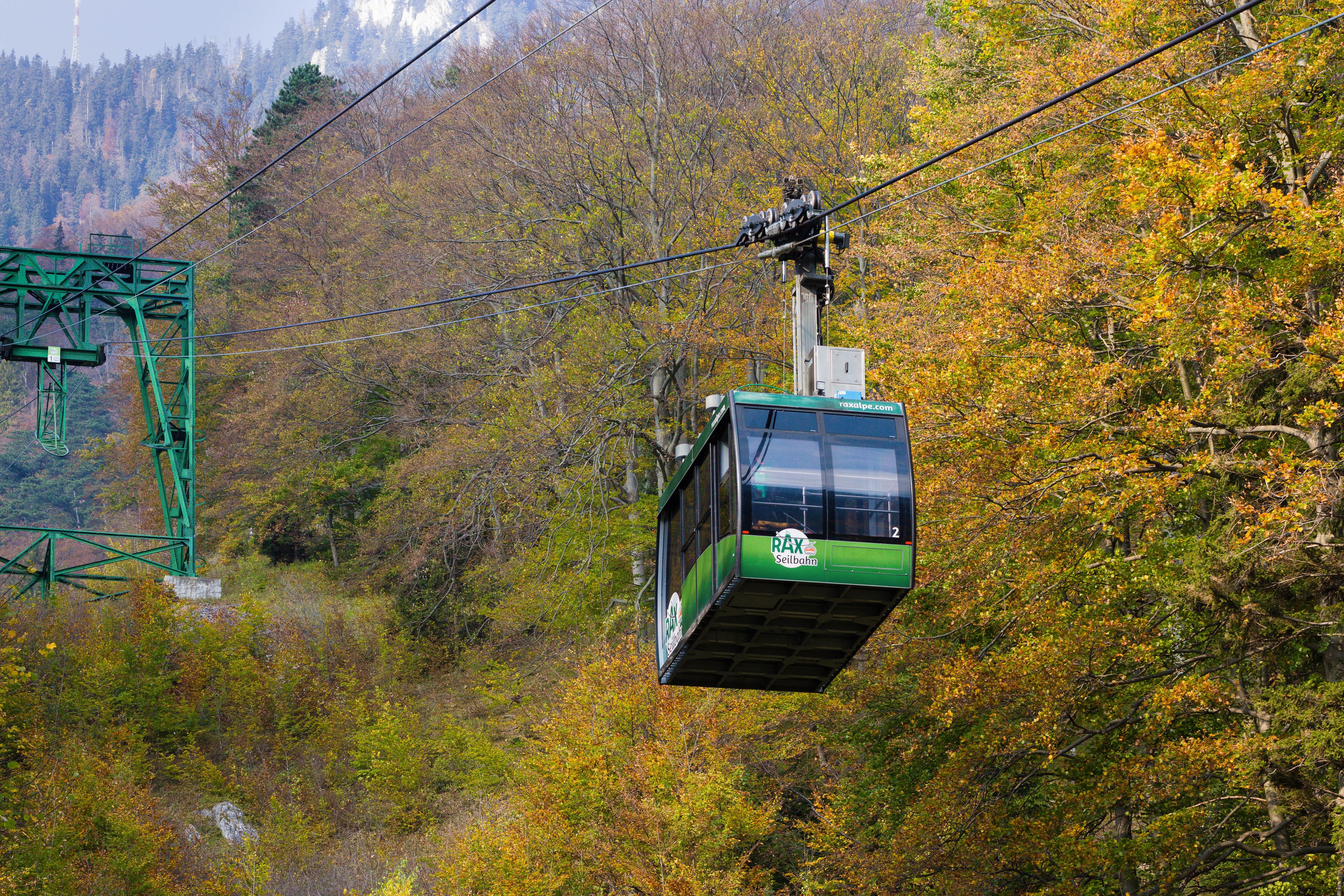 Grüne Rax Seilbahn fährt durch herbstlichen Wald mit buntem Laub.