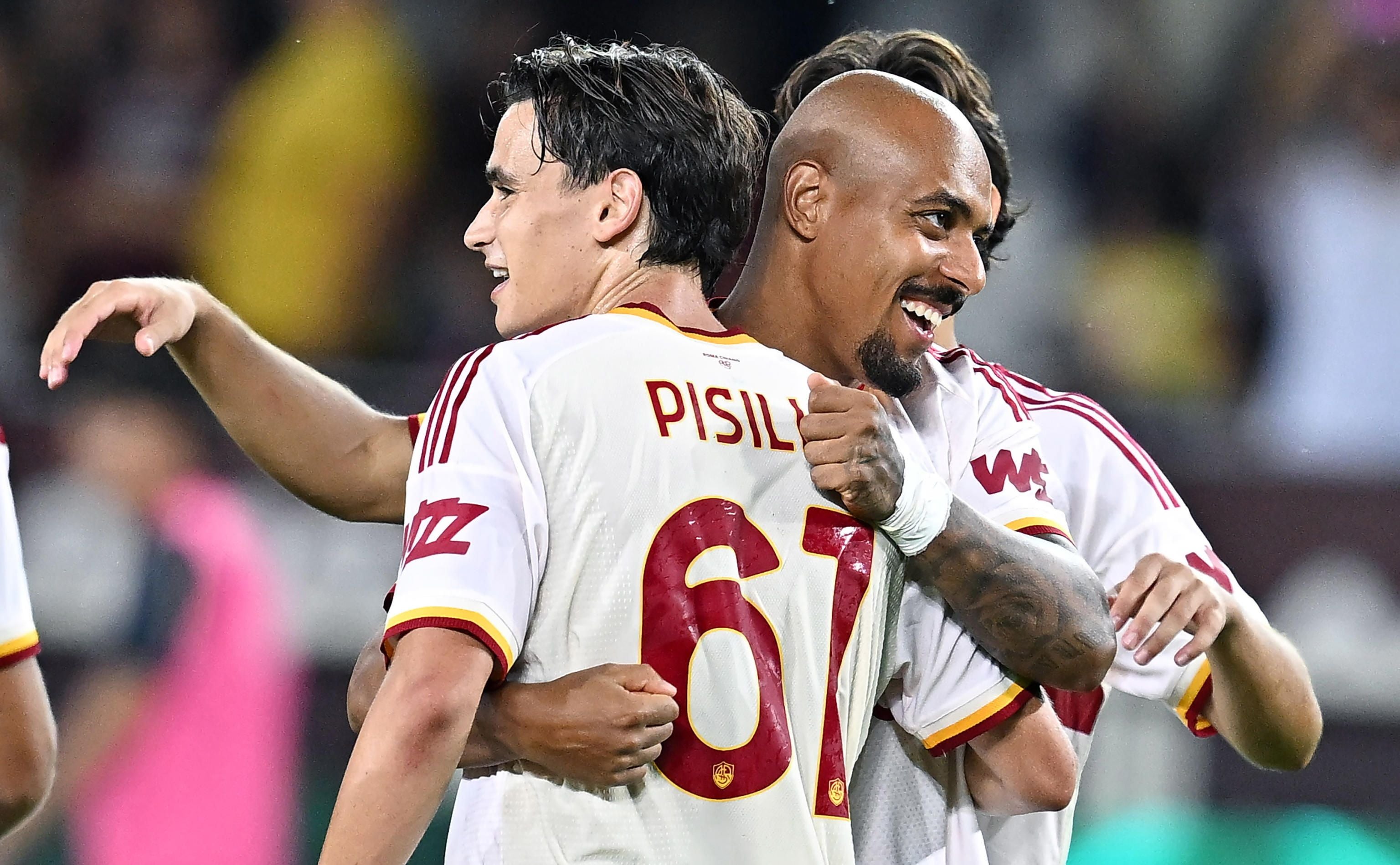 Donyell Malen und Niccolo Pisilli von der AS Roma umarmen sich lachend im weißen Auswärtstrikot nach einem Treffer.