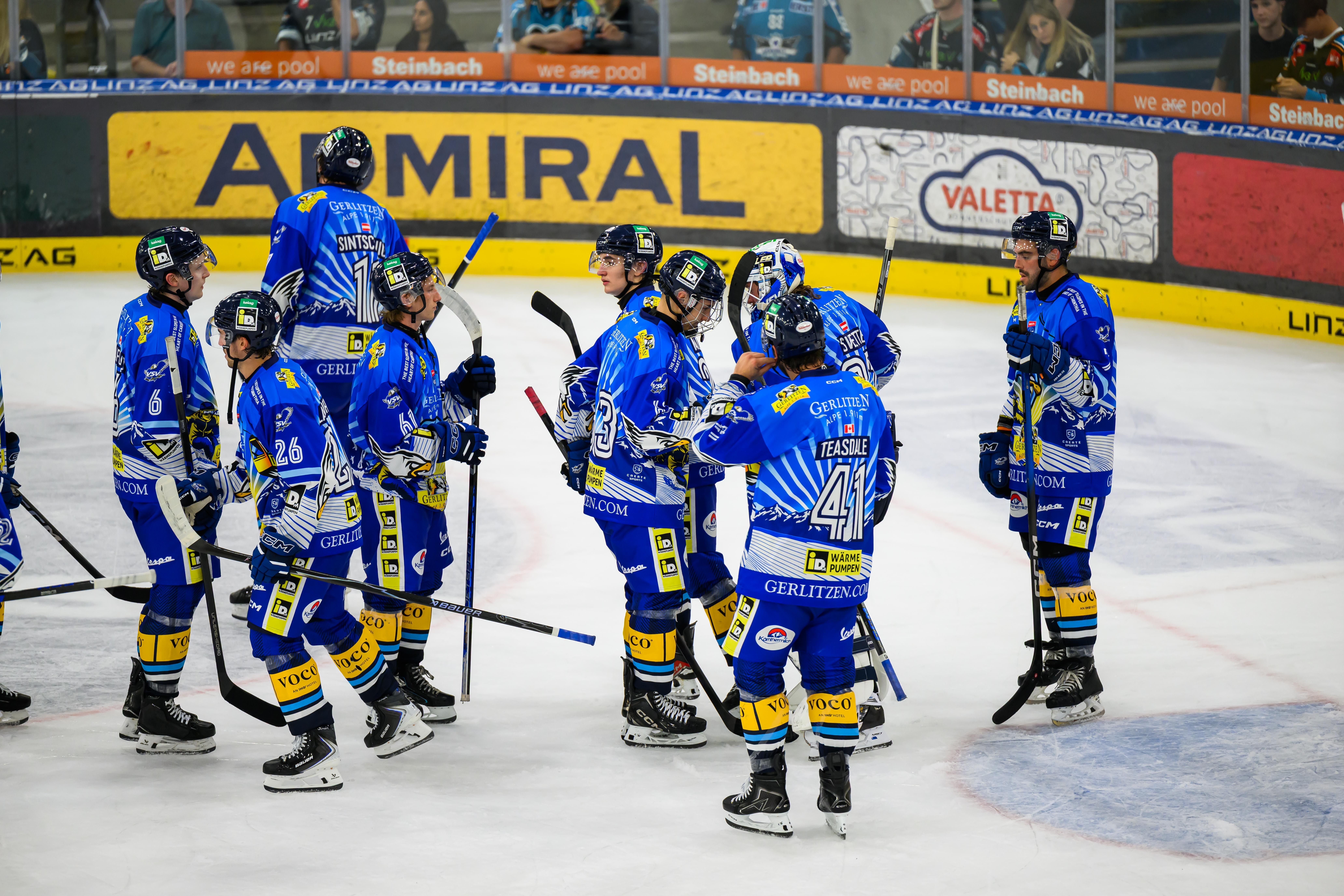 Mehrere Eishockeyspieler des VSV in blauen Trikots zeigen Enttäuschung auf dem Eis.