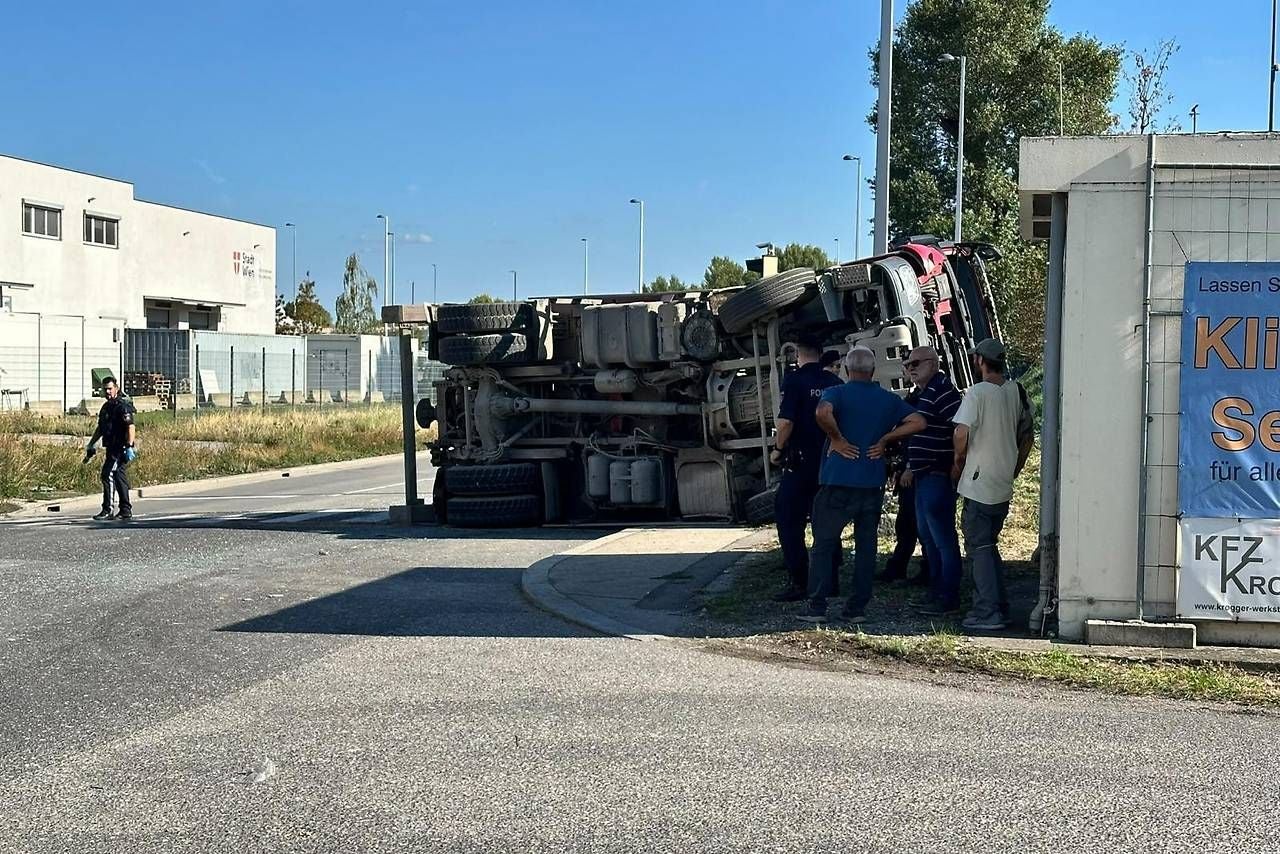 Umgekippter Lastwagen auf Straße, mehrere Personen stehen daneben, Polizei ist vor Ort.