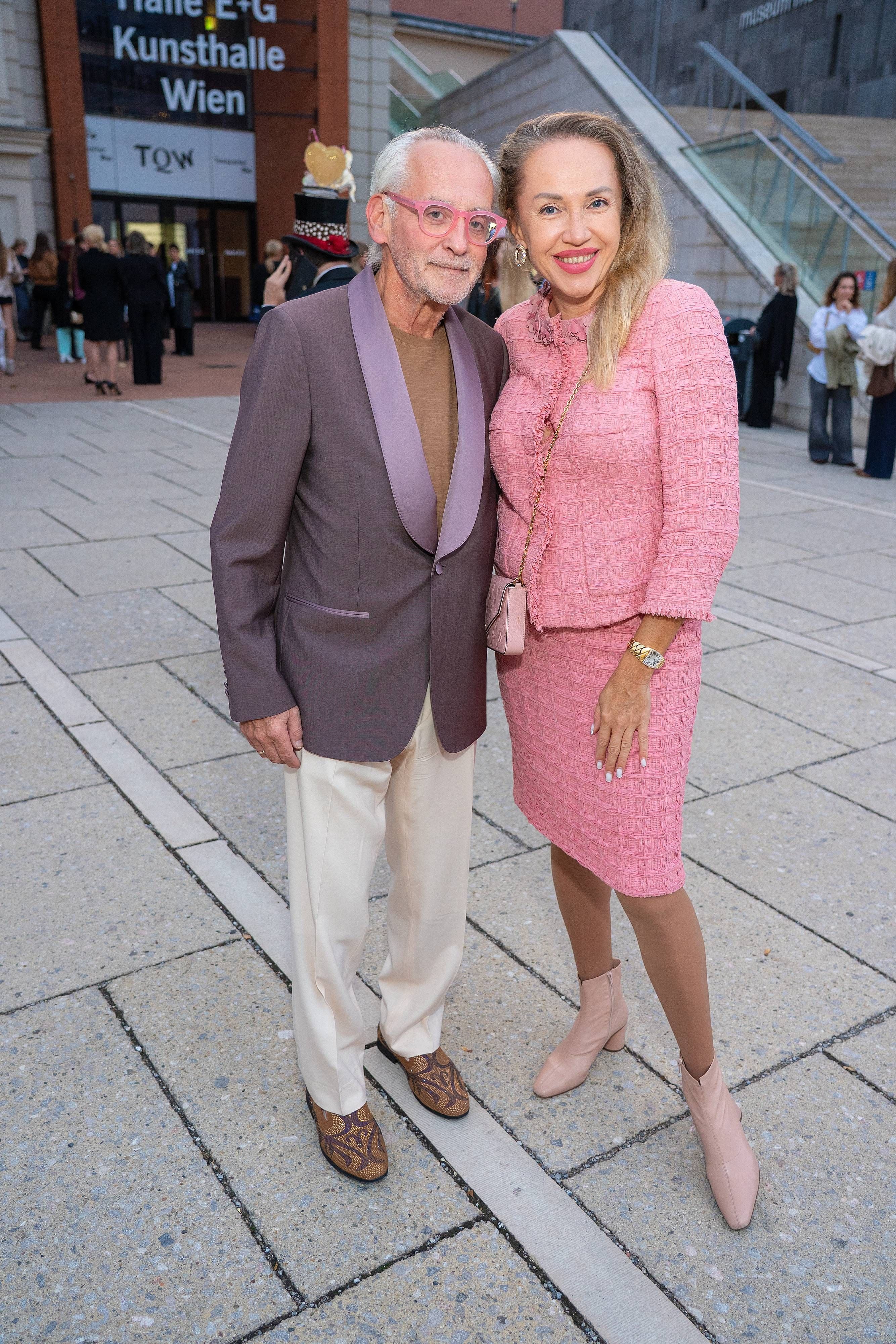 Ein Mann und eine Frau posieren schick gekleidet vor der Kunsthalle Wien im Freien.