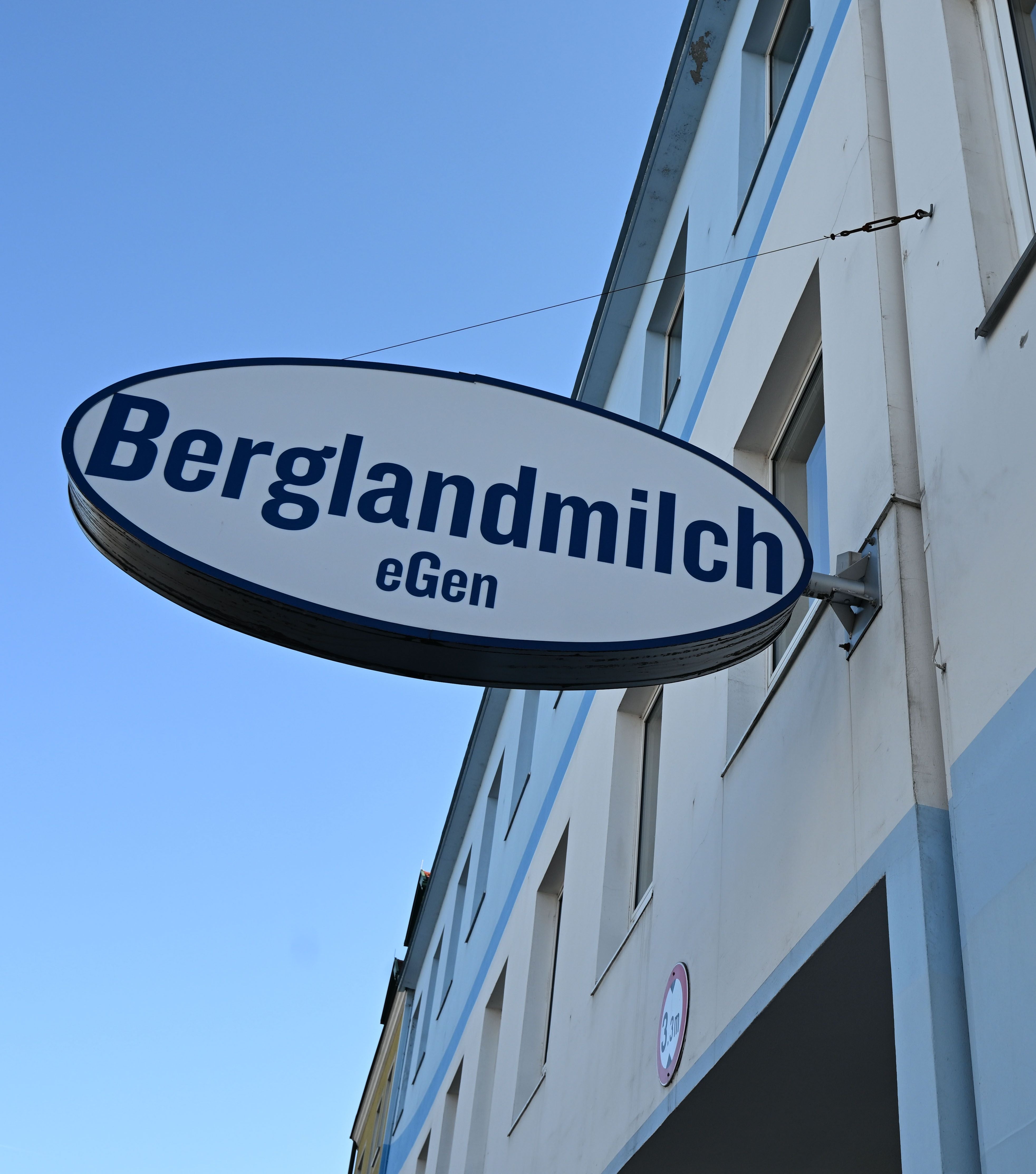 Ovales Firmenschild mit der Aufschrift "Berglandmilch eGen" an einem Gebäude in Wels.