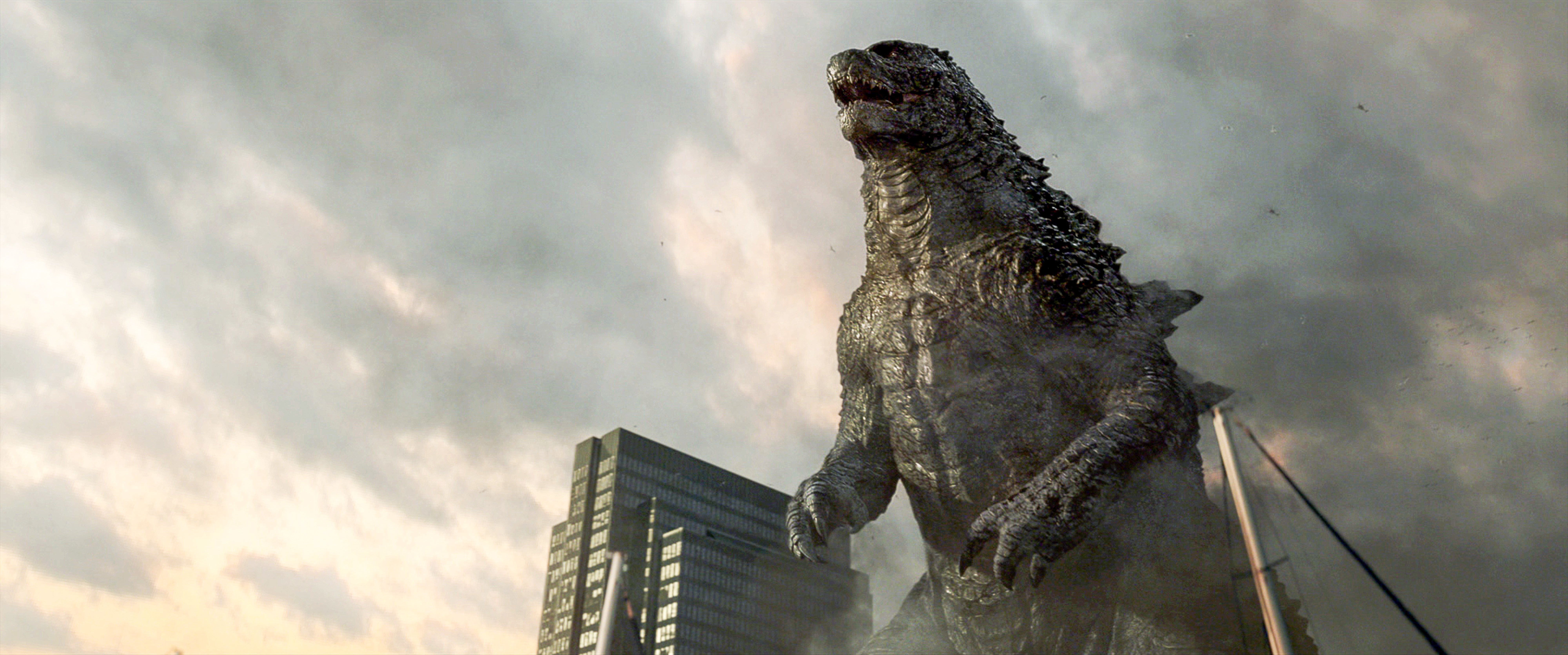 Godzilla erhebt sich zwischen Wolkenkratzern in einer rauchigen, zerstörten Stadtlandschaft.